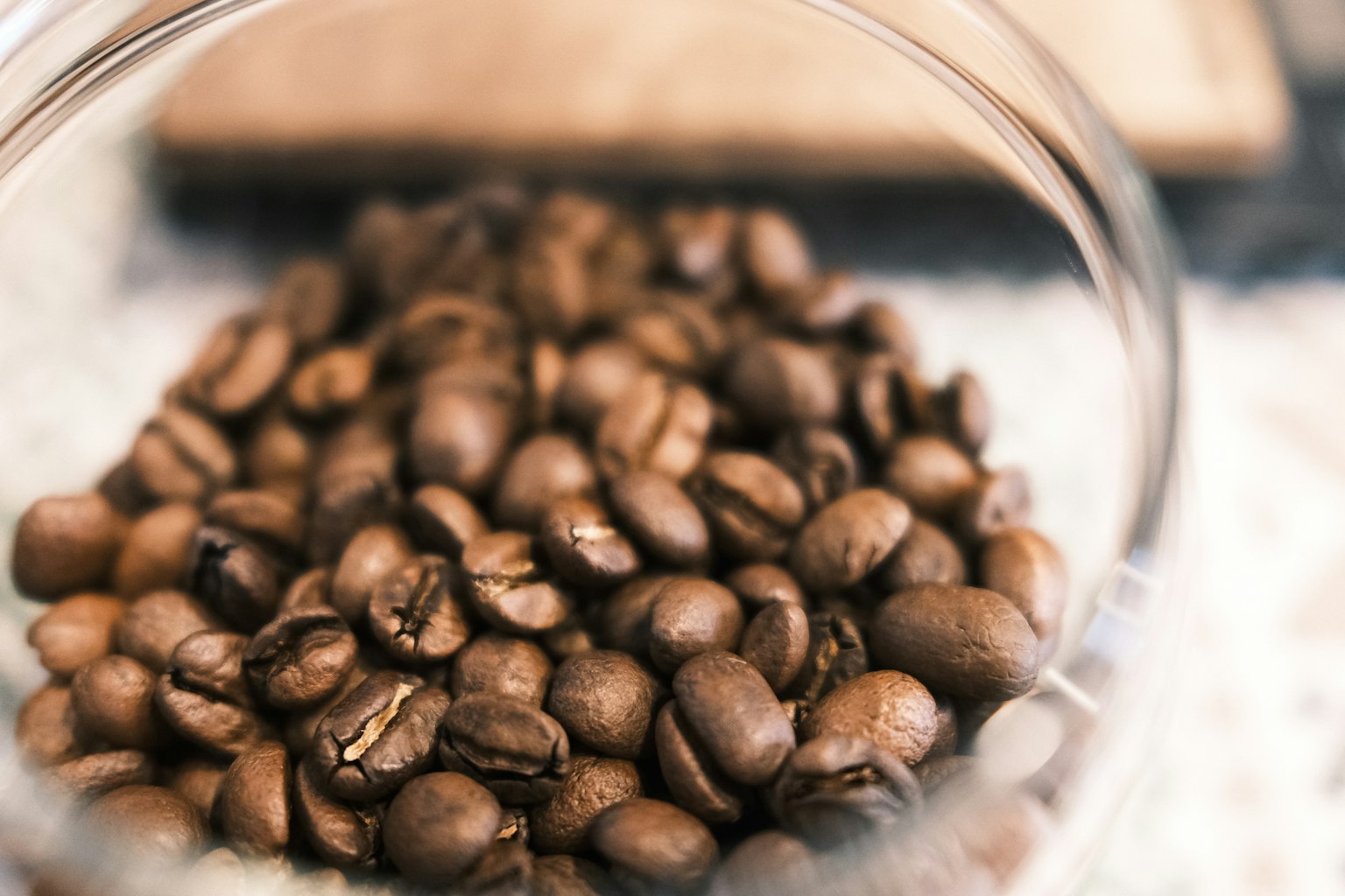 Primer plano de granos de café tostados en un recipiente transparente