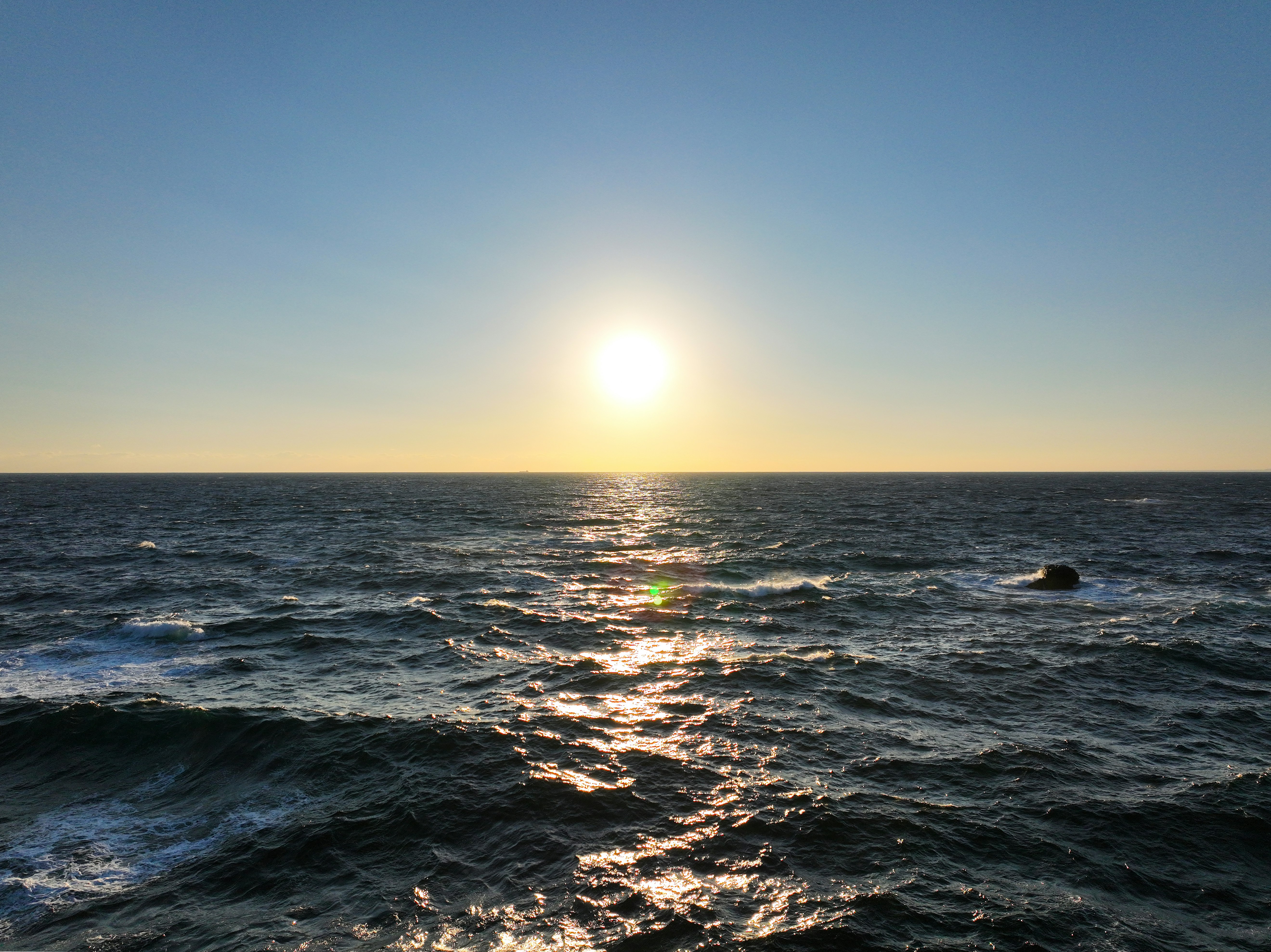海の上に沈む夕日と波の反射