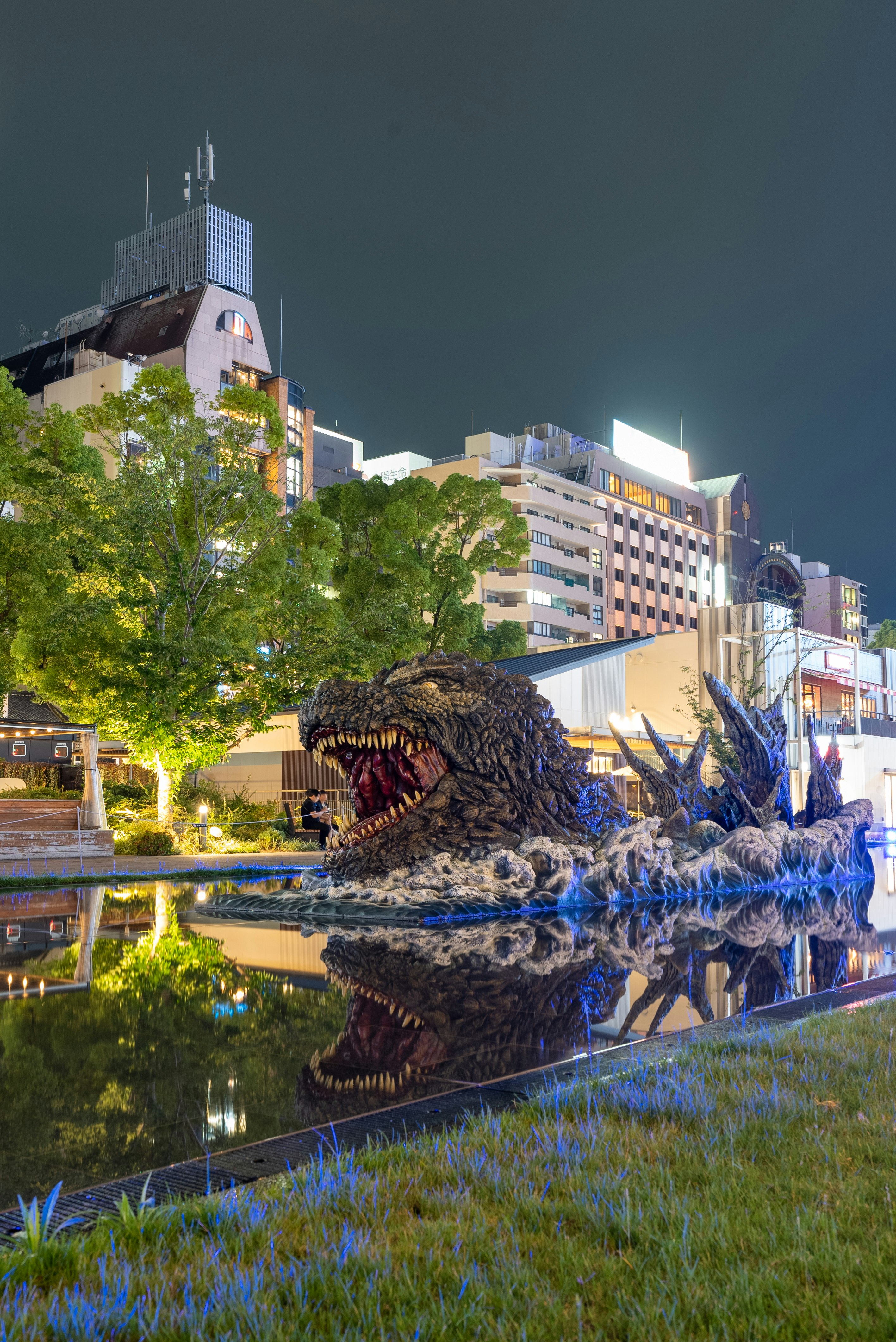 恐竜のモニュメントと夜の街並み