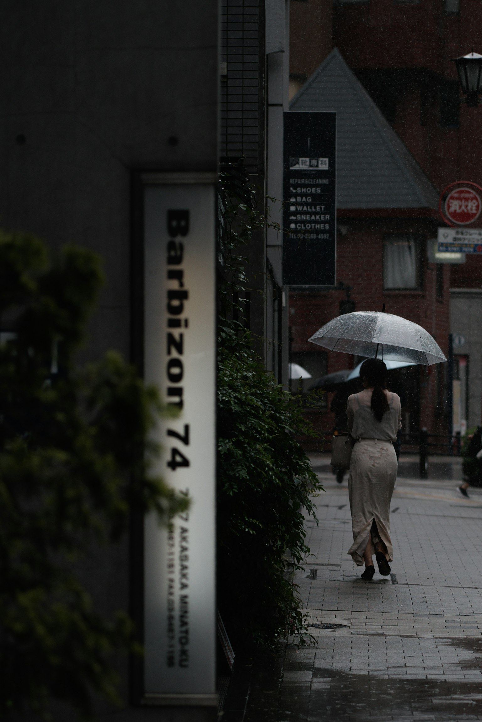巴爾比宗74的標誌和一位撐著傘在雨中行走的女性