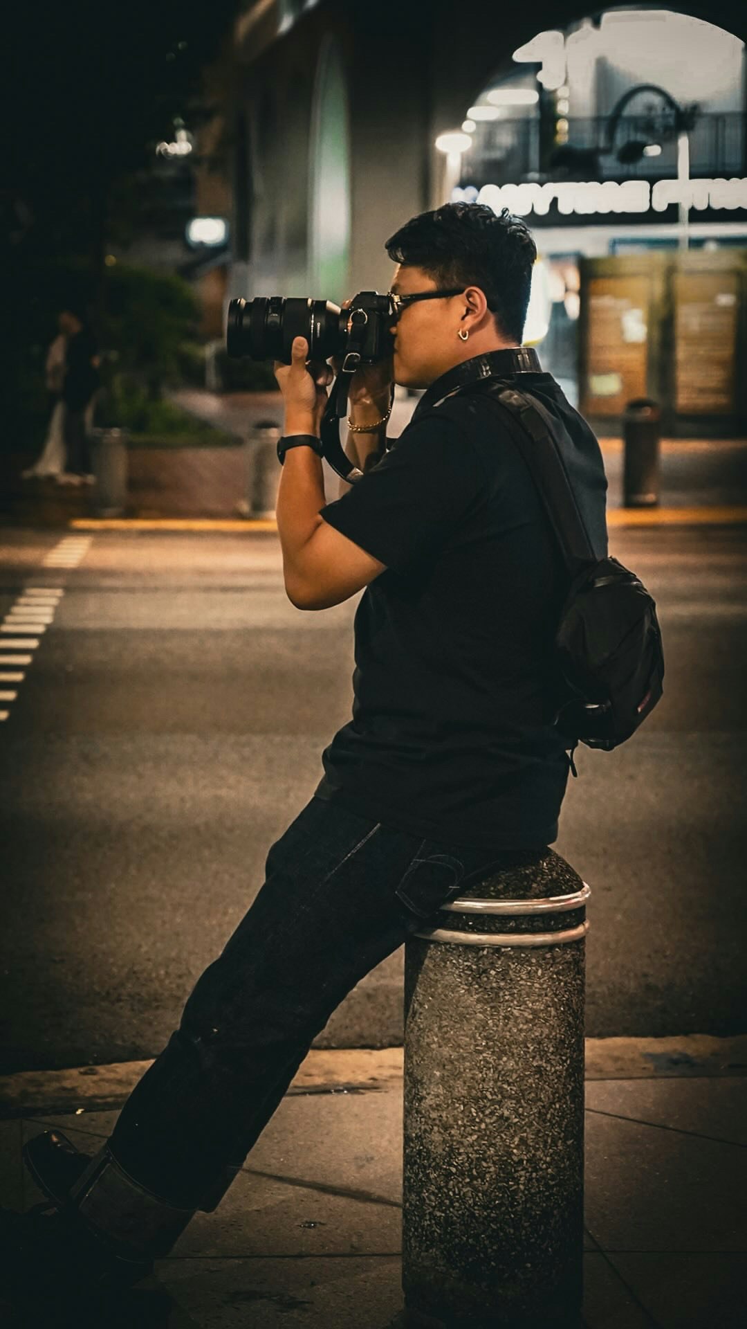 Person mit Kamera an einer nächtlichen Straßenecke