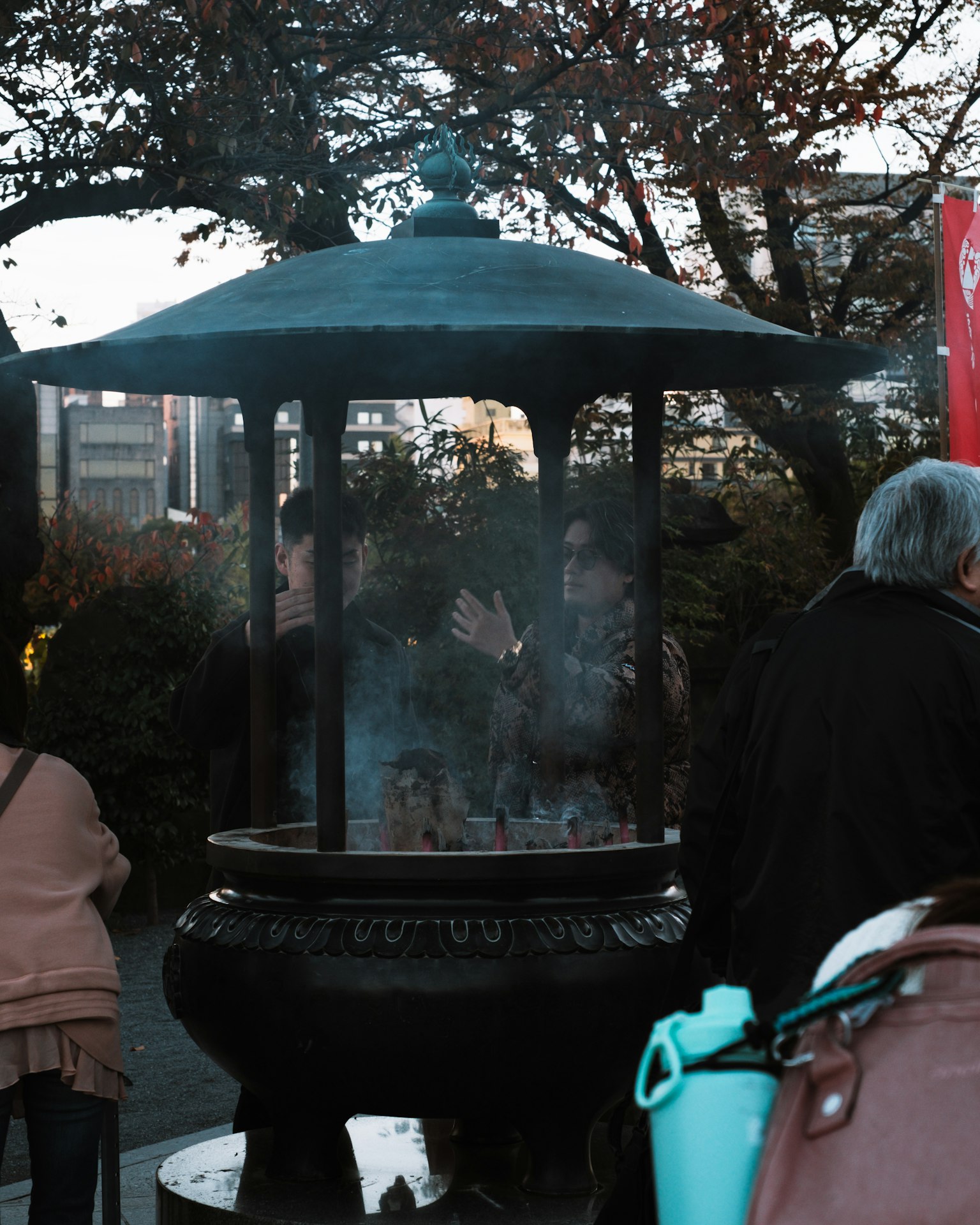 People gathered around a black incense burner with smoke rising