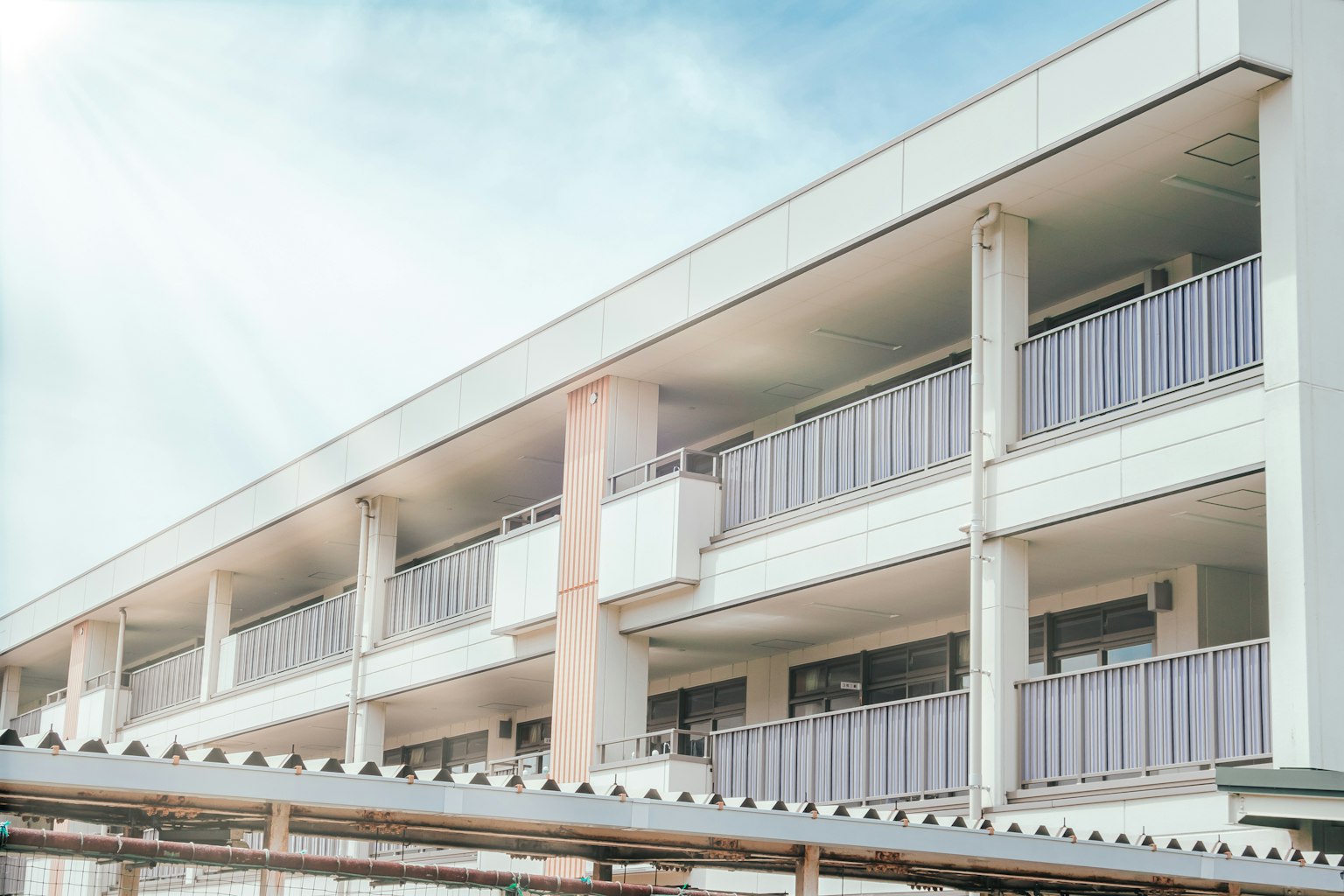 Parte di un edificio residenziale con pareti bianche e cielo azzurro