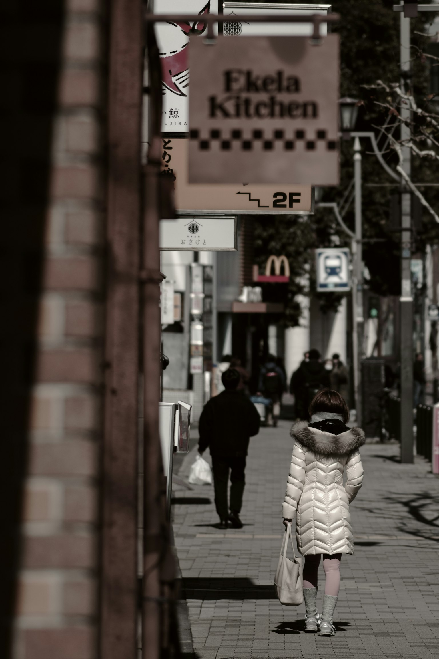 People walking down a street with an Eclair Kitchen sign