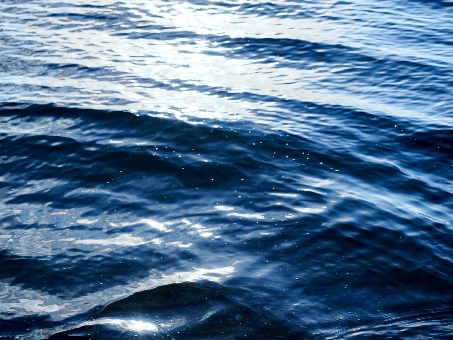 Superficie de olas oceánicas azules con reflejos