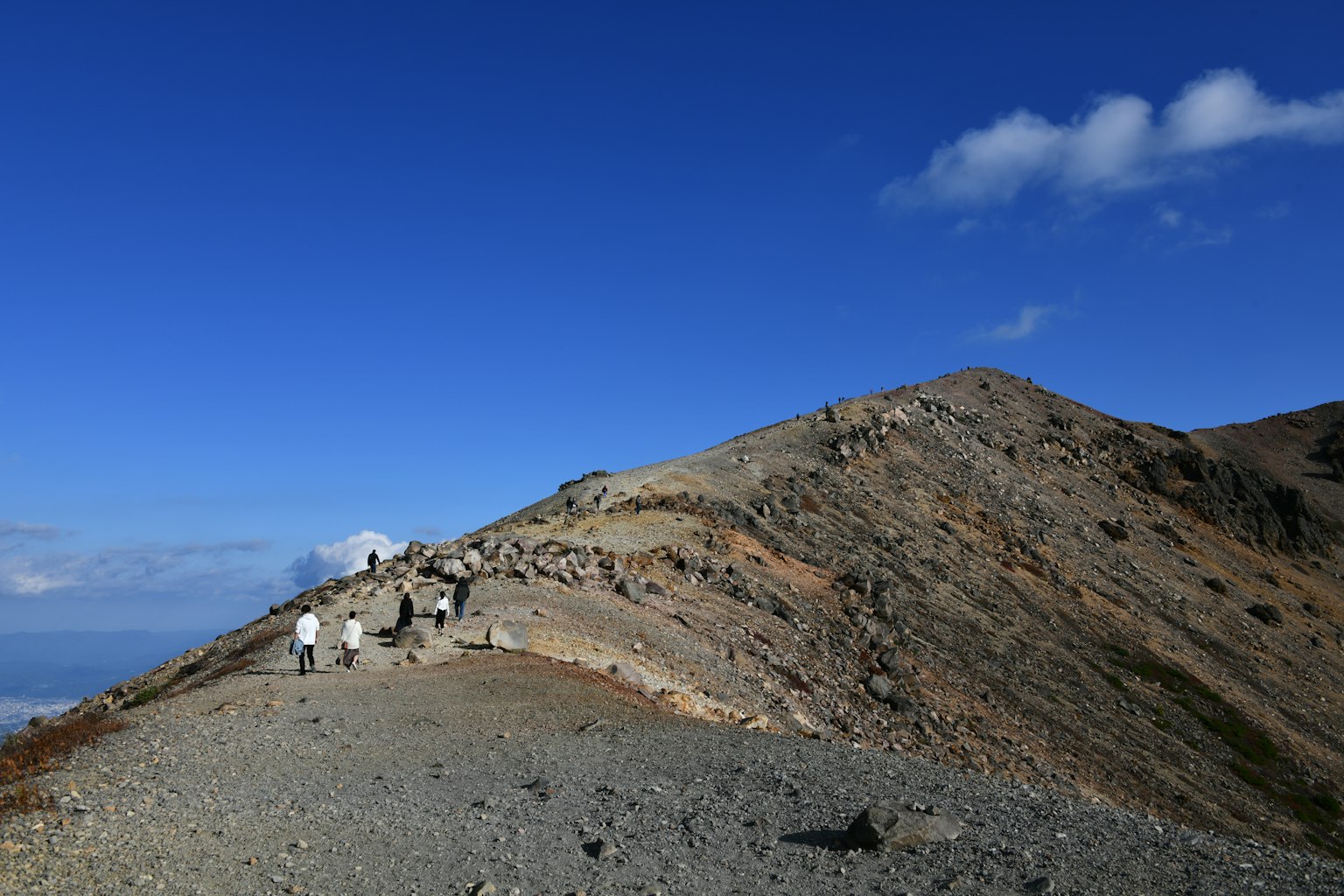 Randonneurs sur une crête de montagne sous un ciel bleu avec des nuages