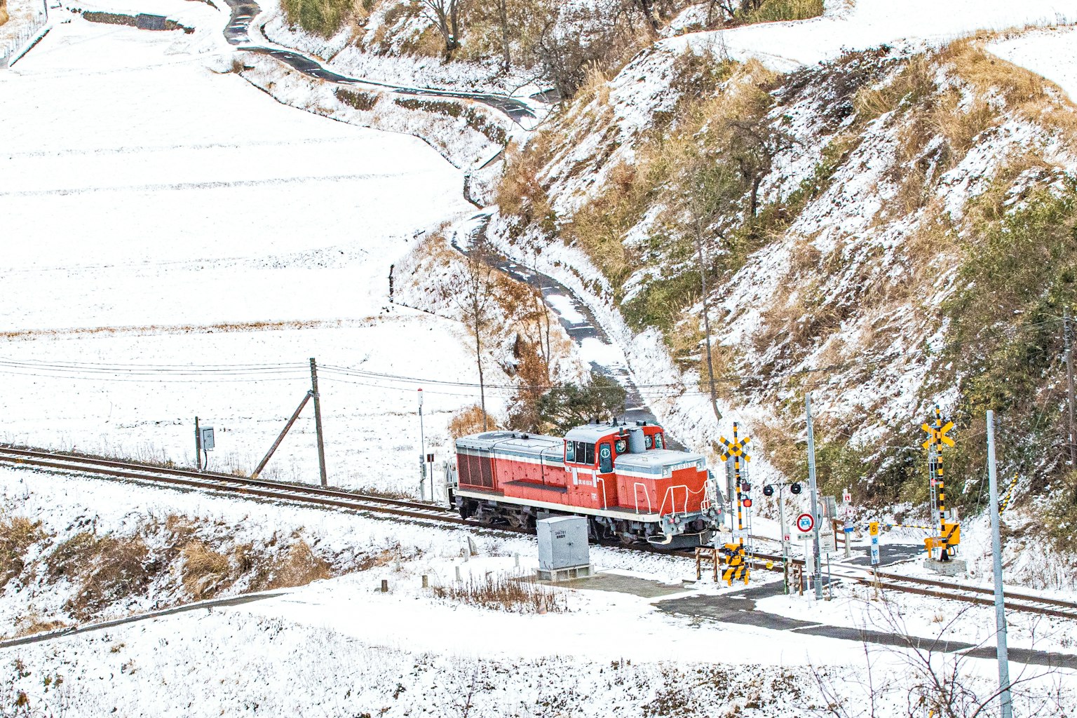 Red locomotive traveling through a snowy landscape