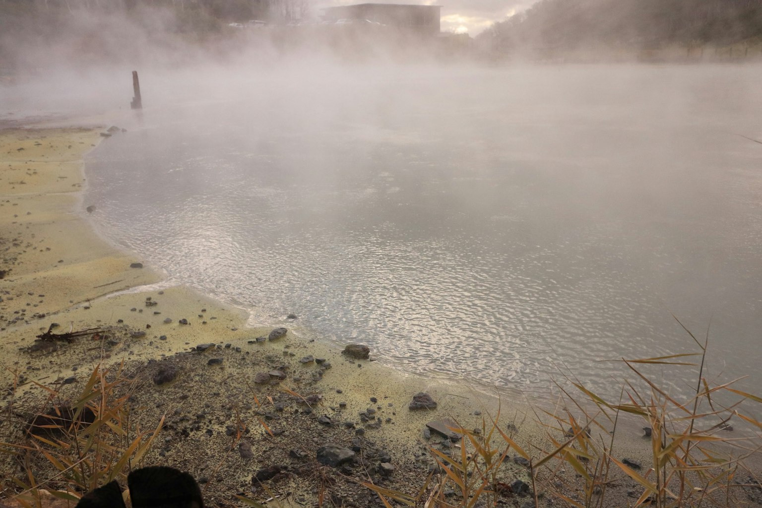 Orilla brumosa con agua termal y terreno rocoso