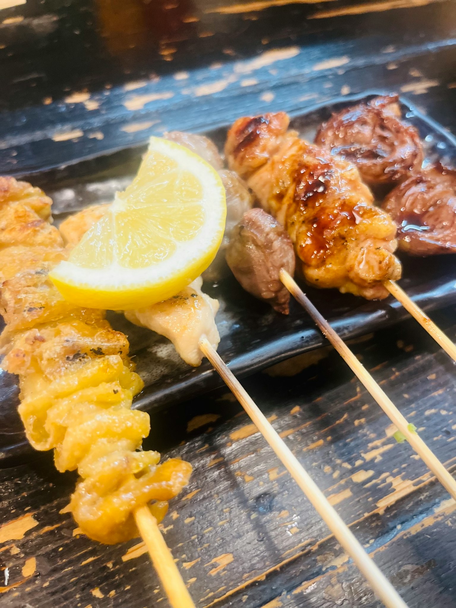 黑色盘子上的烤鸡肉串配一片柠檬