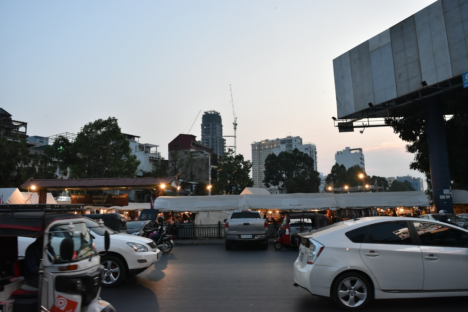 ทิวทัศน์เมืองในยามพลบค่ำ มีรถจอดและเงาของตึกสูง