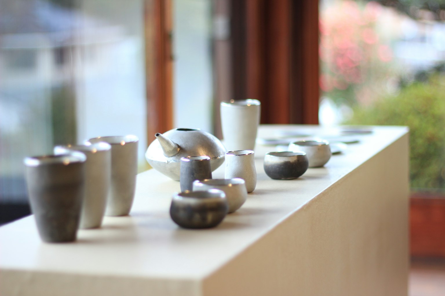 Display of various shaped and colored pottery on a white pedestal