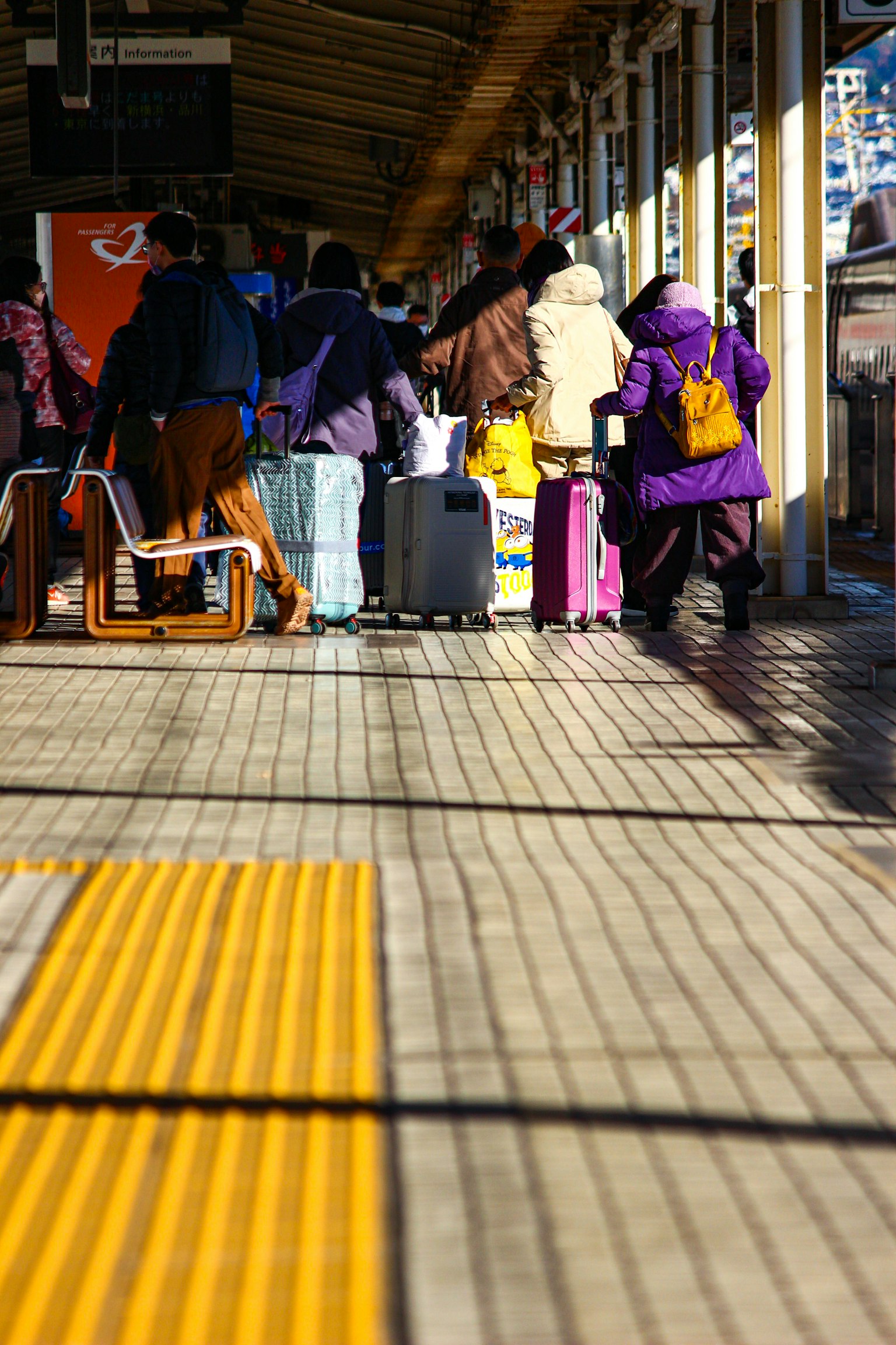 駅のプラットフォームで荷物を持った人々が並んでいる様子