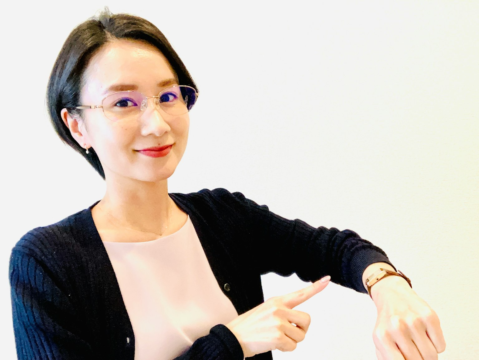 一位女性微笑著指著她的手錶