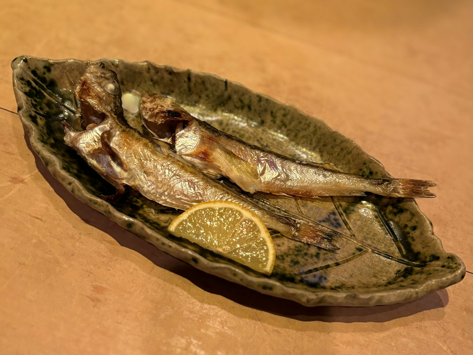 Pescado a la parrilla en un plato en forma de hoja con una rodaja de limón