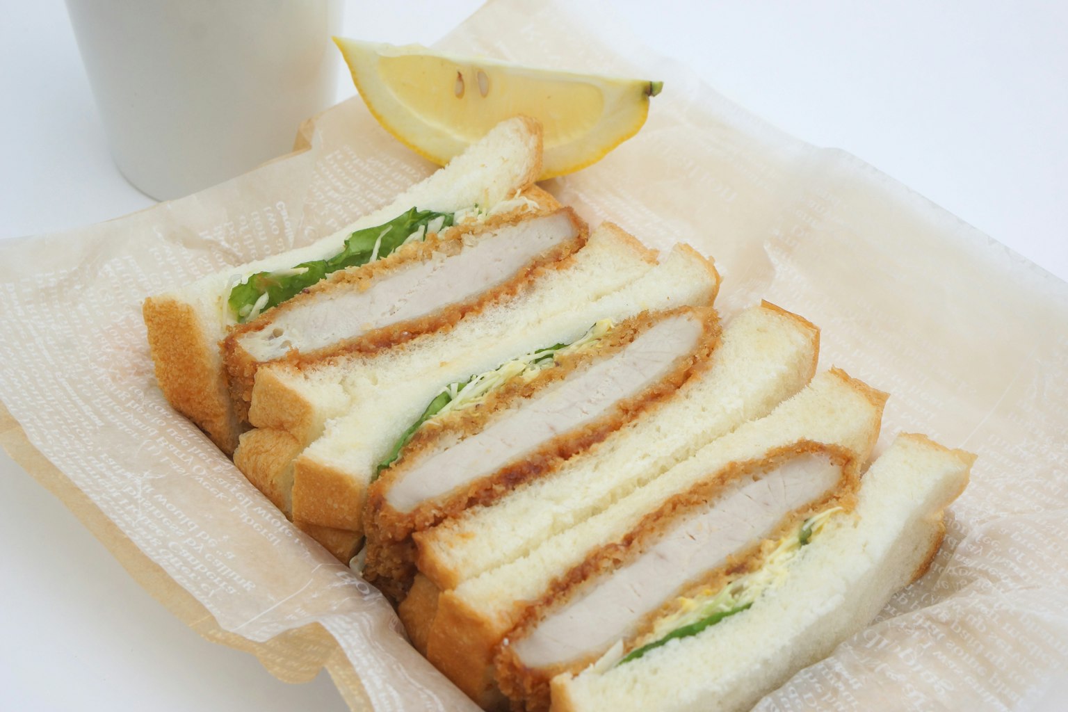 Panino tonkatsu affettato con lattuga e uno spicchio di limone