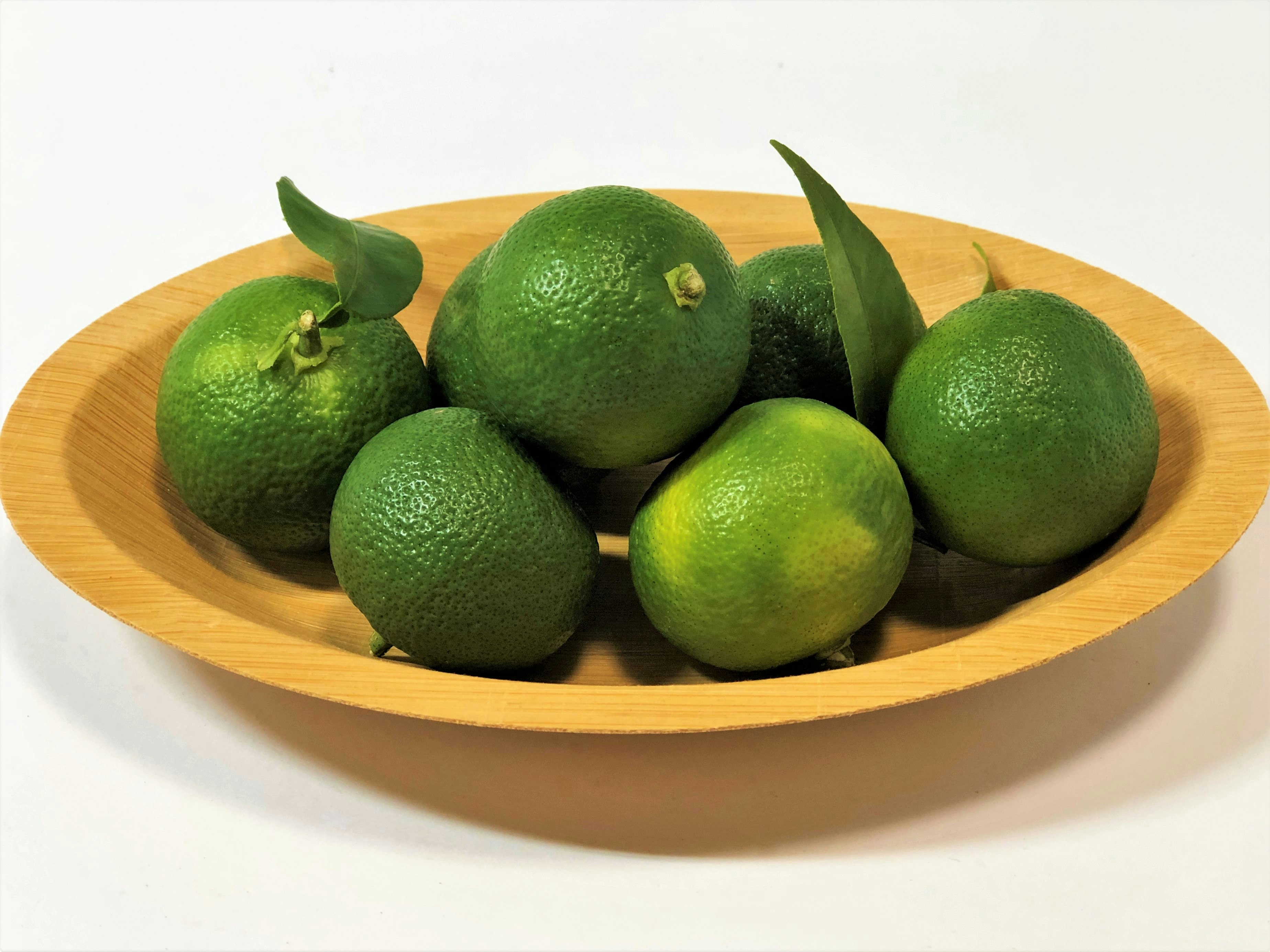 Green limes on a wooden bowl
