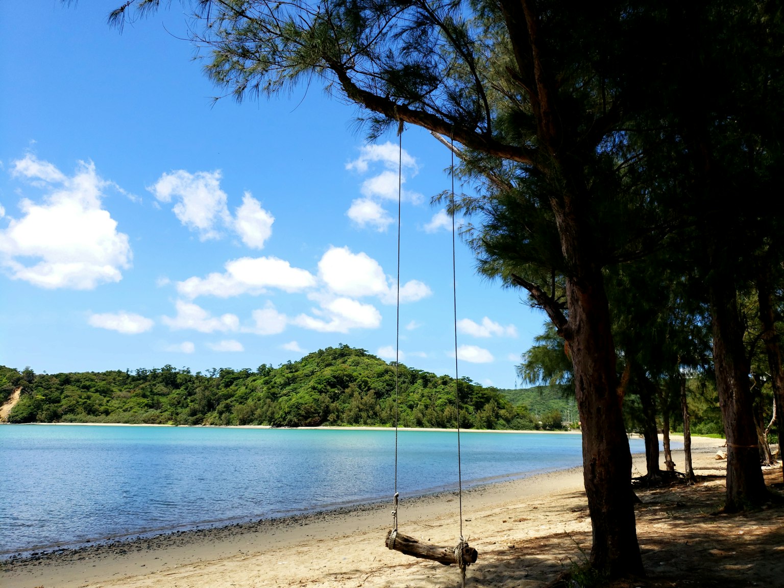 Ayunan yang tergantung di pantai dikelilingi oleh air biru dan bukit hijau