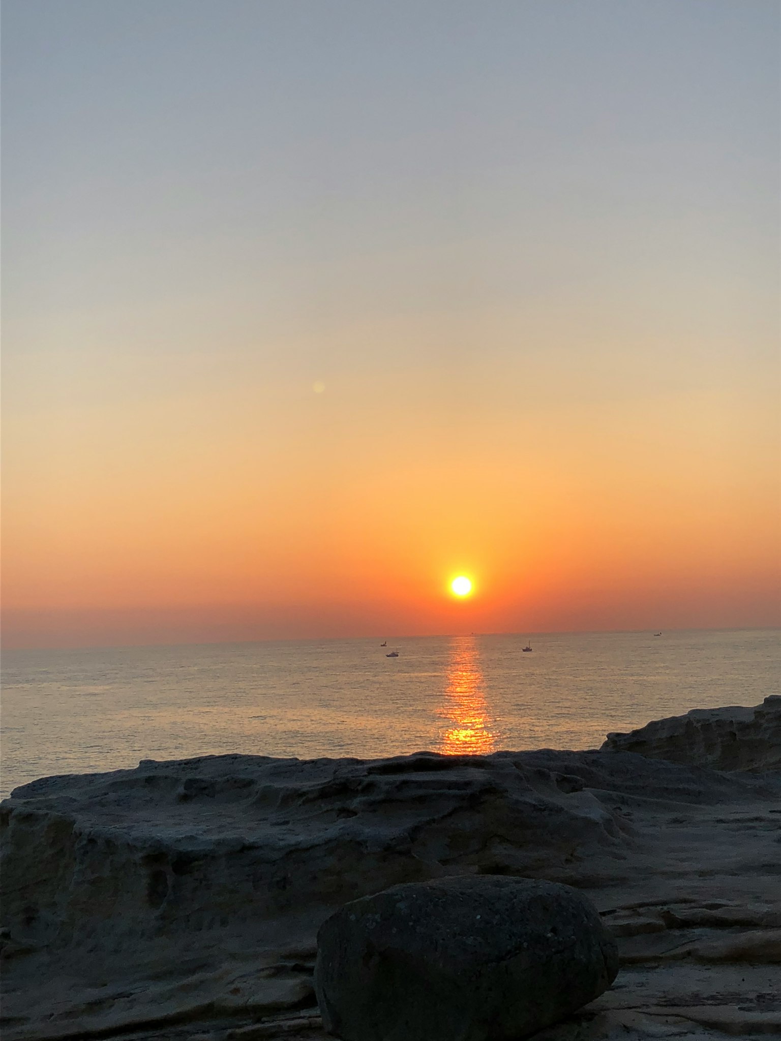 Vista bellissima del tramonto sull'oceano con rocce in primo piano