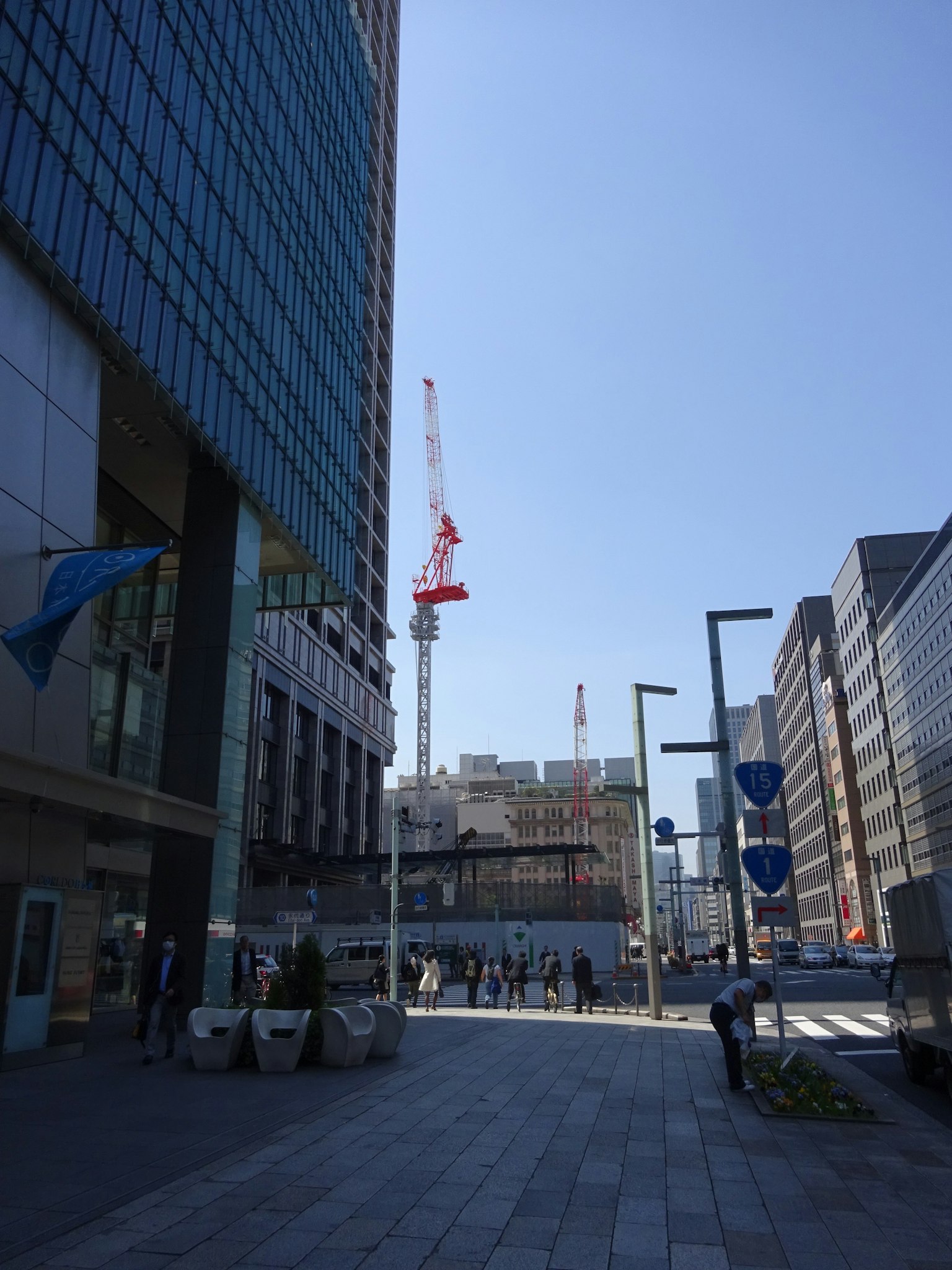 Urban landscape featuring a high-rise building and a construction crane under a blue sky
