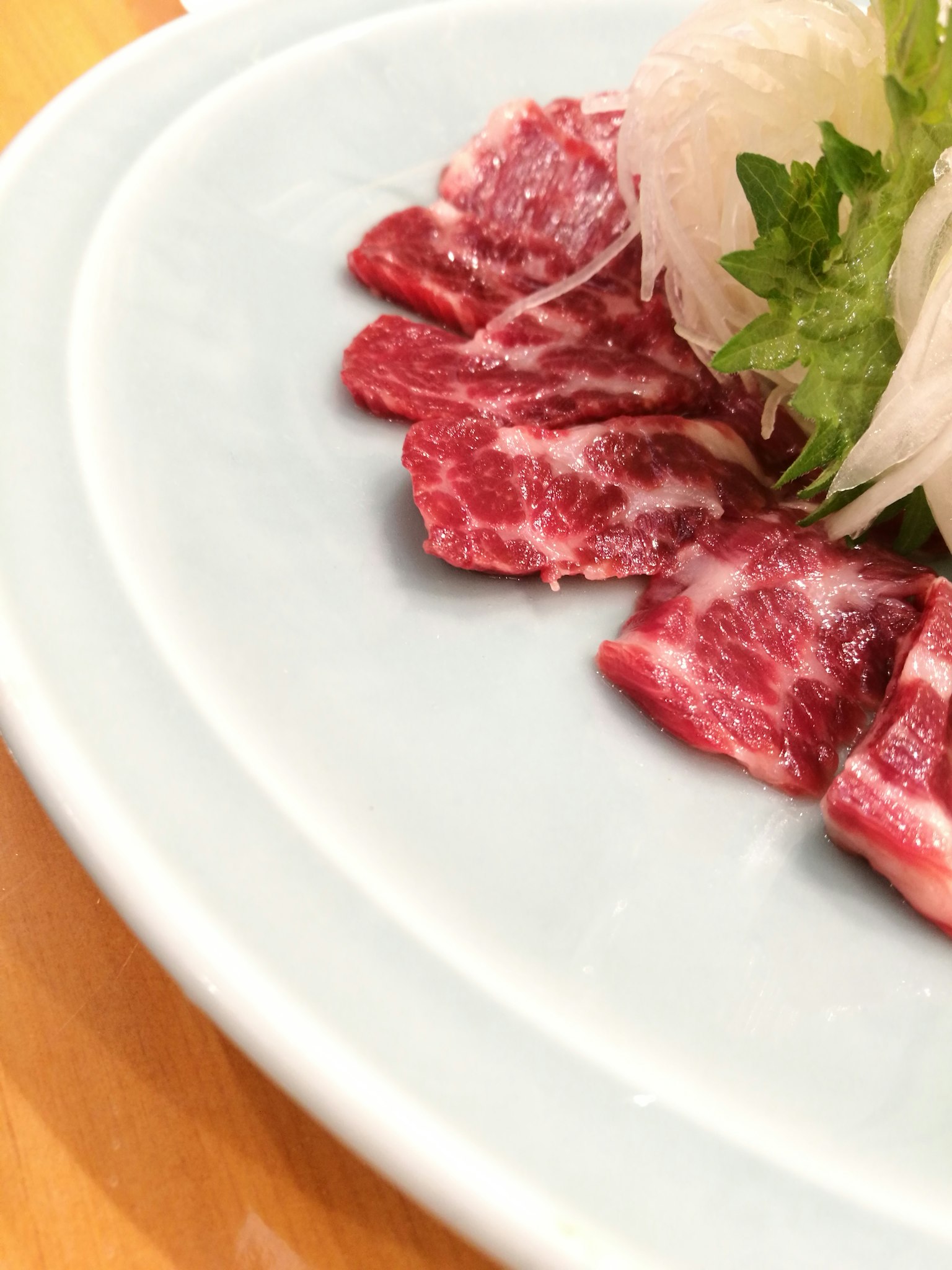 Dünn geschnittenes Fleisch und Daikon-Salat auf einem weißen Teller