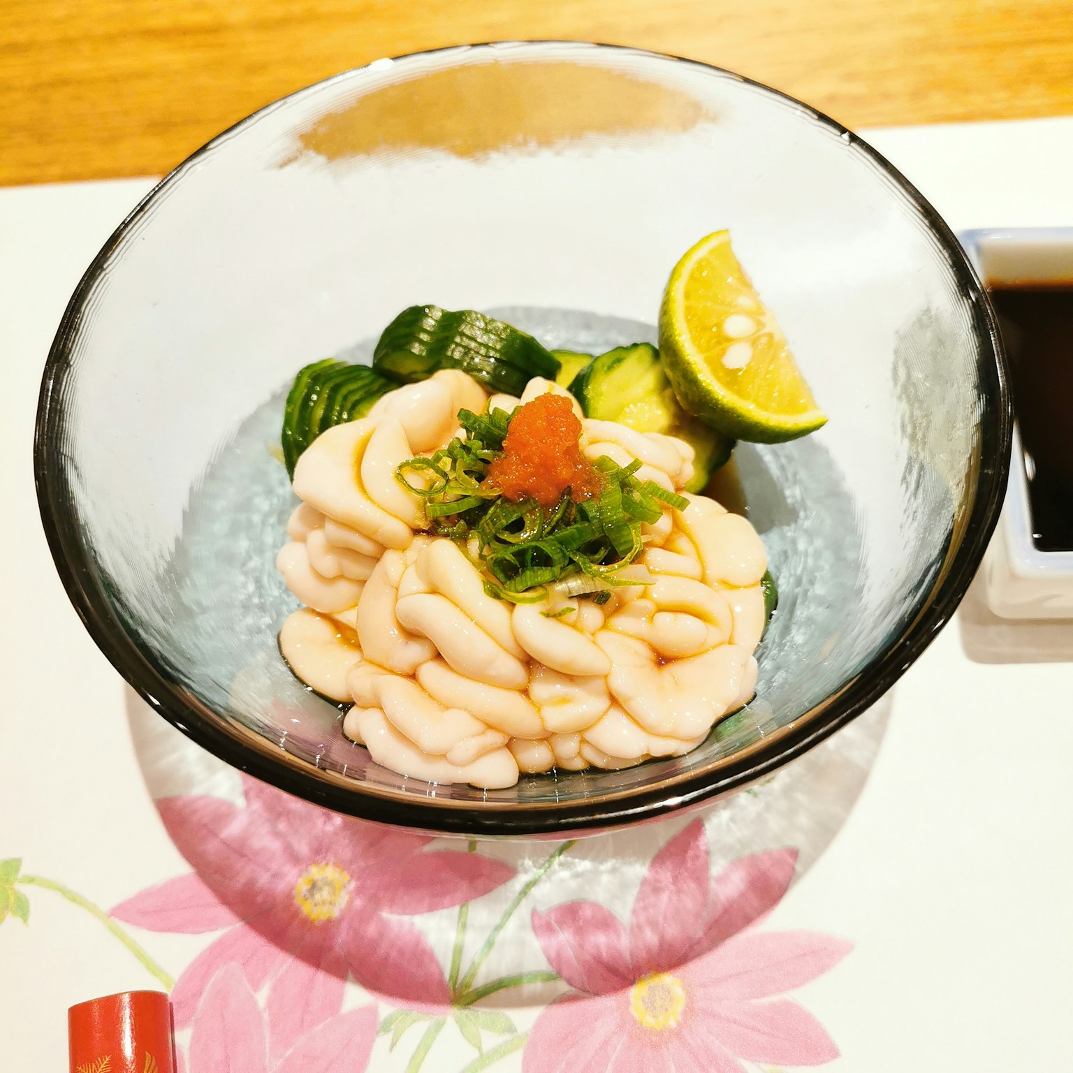 一碗精緻的生魚片，搭配黃瓜片和青檸角