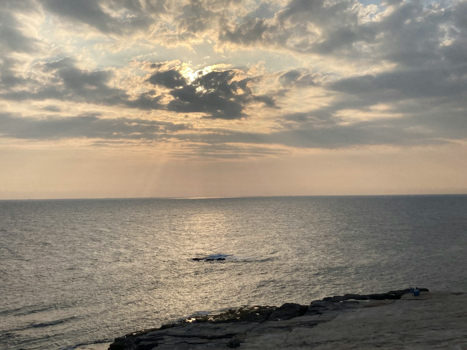 Calm sea and cloudy sky scene with sunlight breaking through clouds
