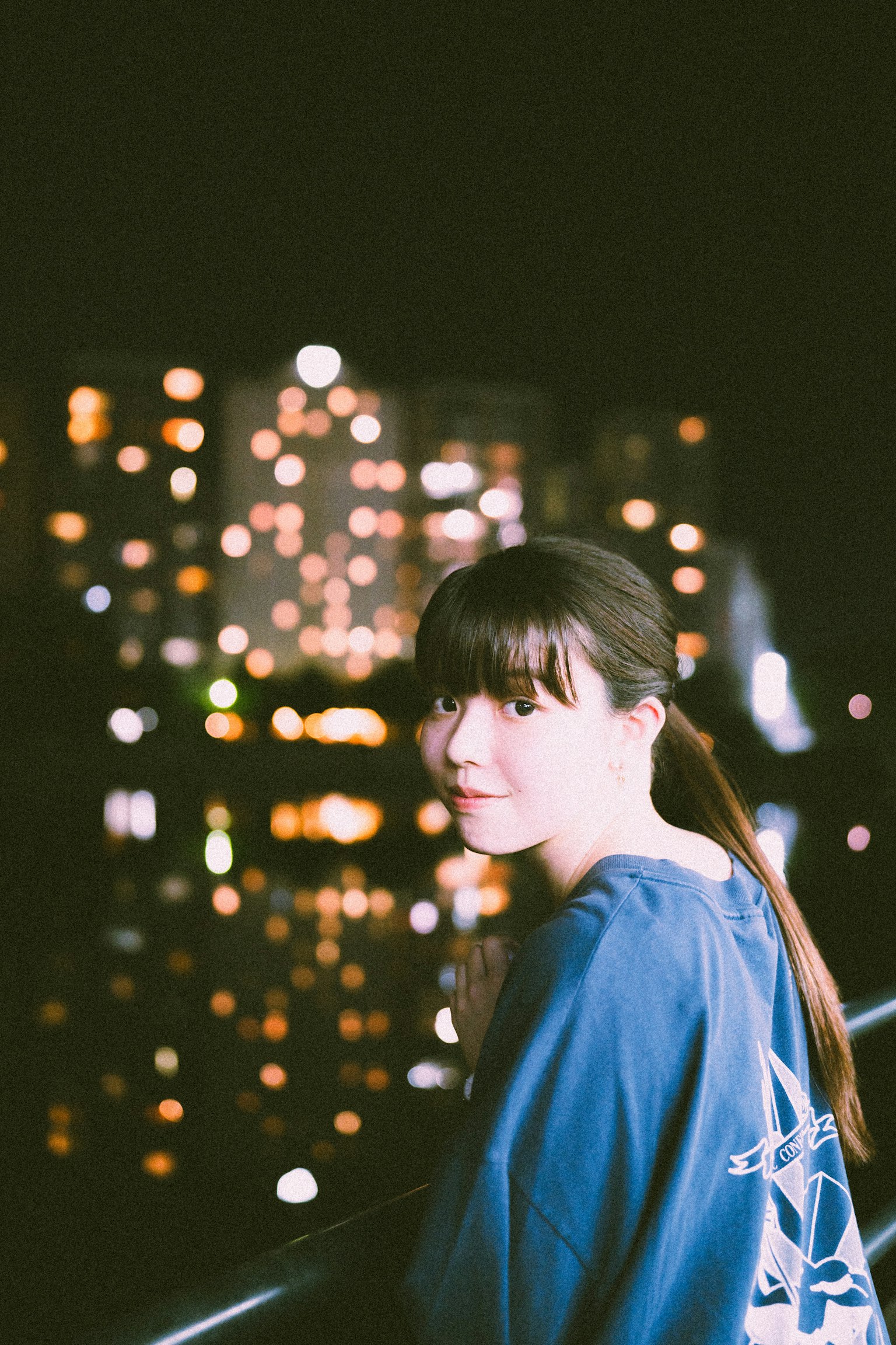 穿着蓝色衬衫的女性肖像，背景是城市夜景