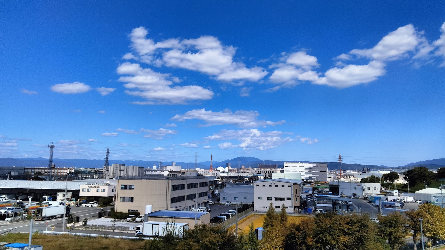 Paisaje industrial bajo un cielo azul con nubes blancas