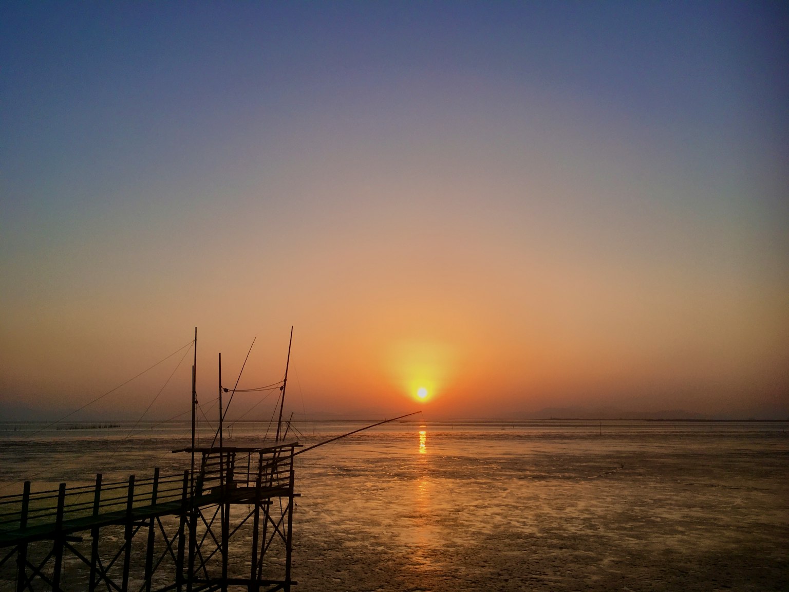 Paesaggio mozzafiato di un tramonto sull'oceano con un molo che si estende nell'acqua