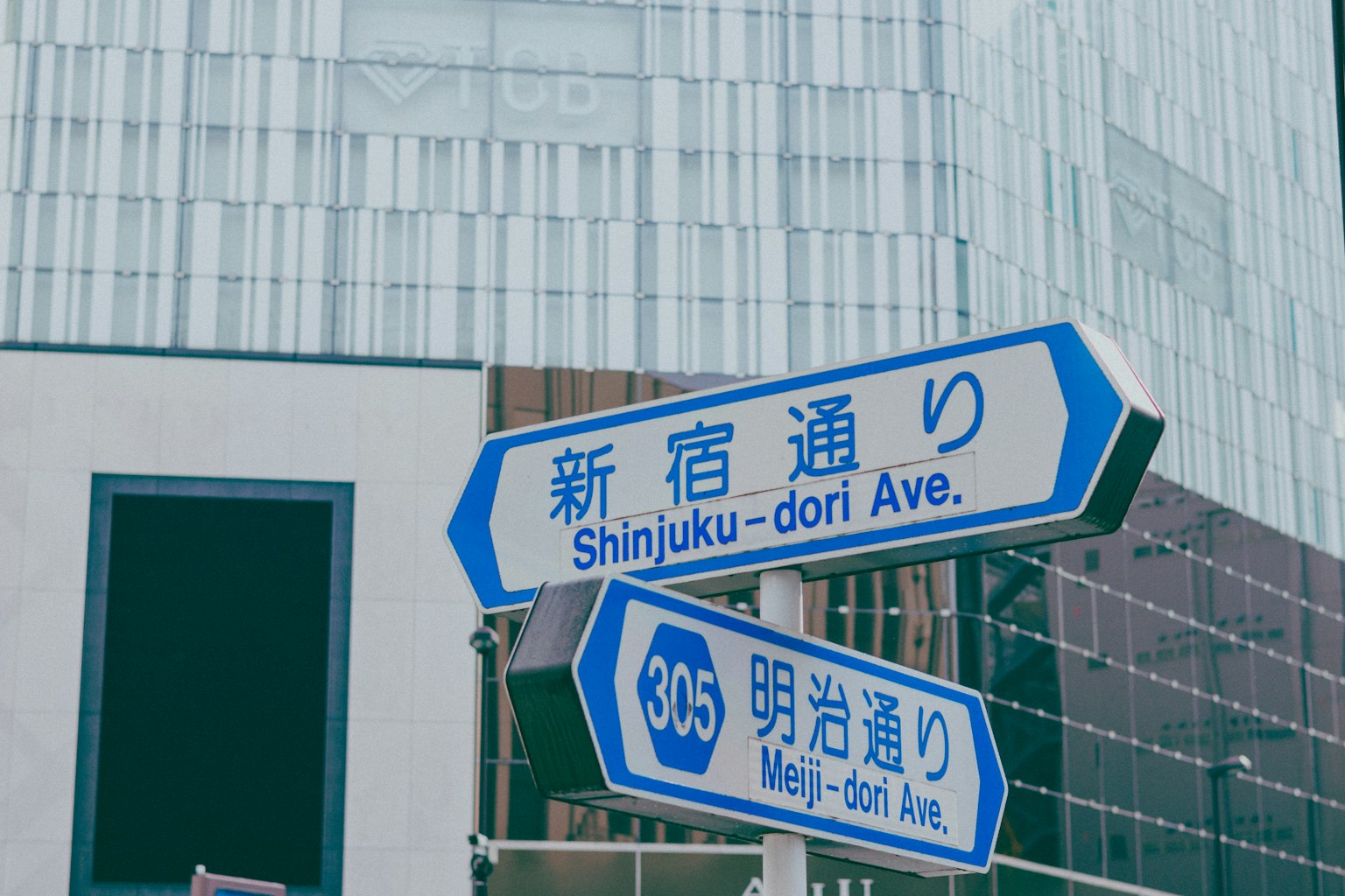 新宿通和明治通的蓝色街道标志与现代建筑