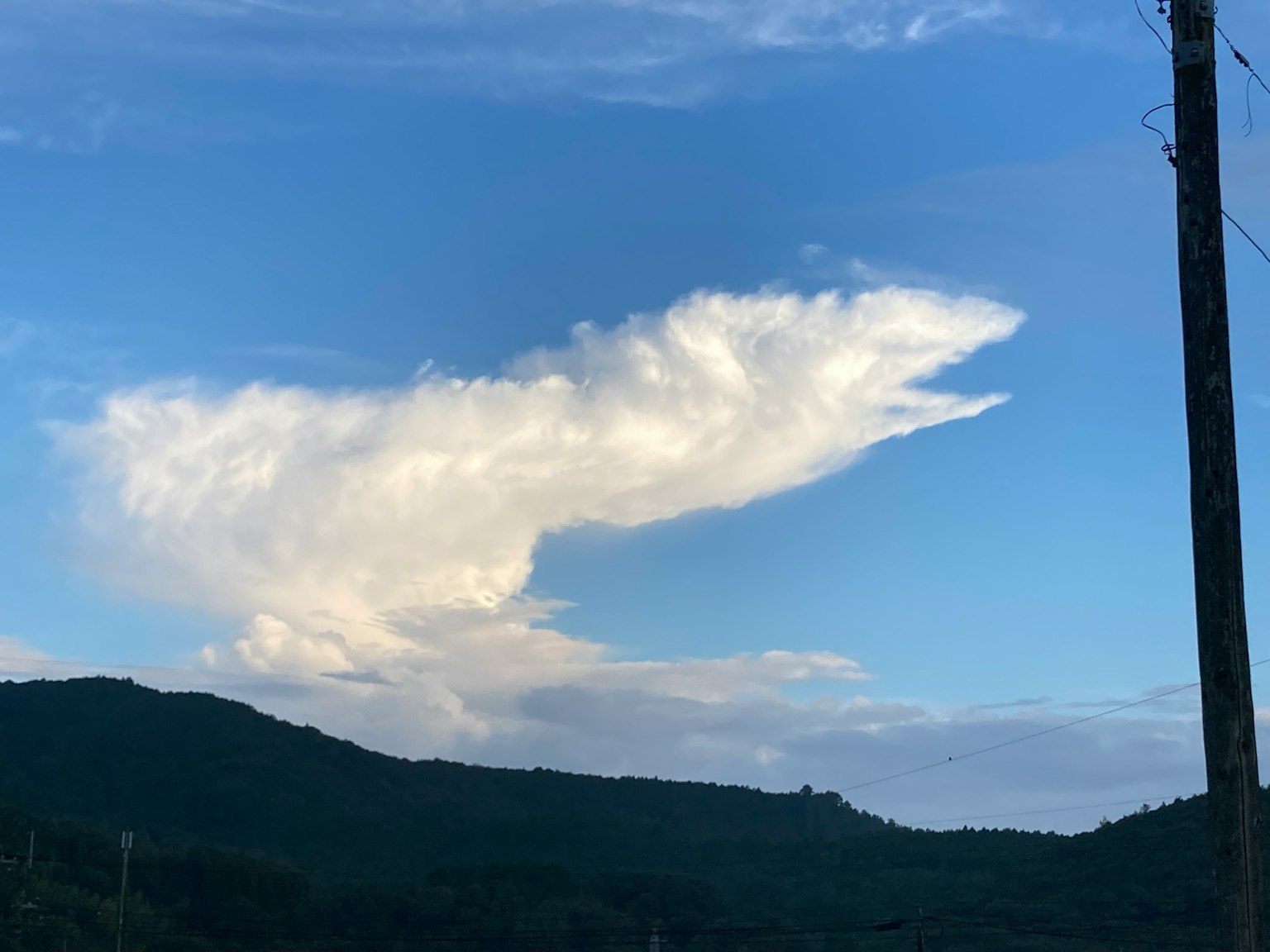 Nube de forma única en el cielo azul con silueta de montaña