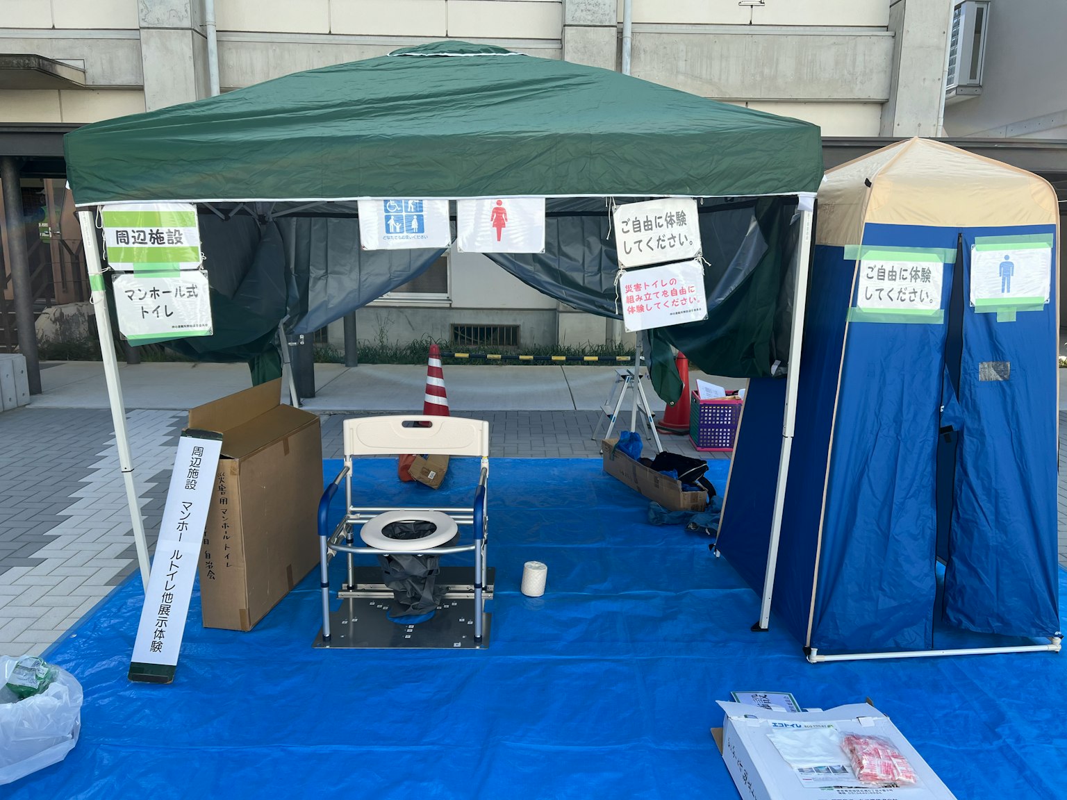 Tenda hijau dengan toilet biru di atas terpal biru