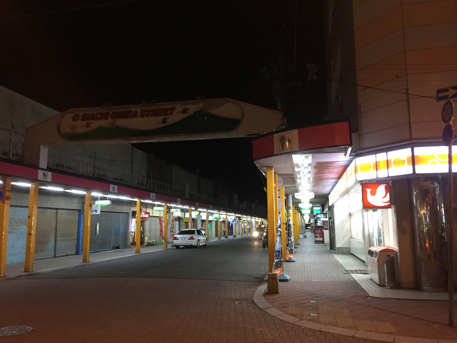 Jalan tenang di pasar malam dengan toko-toko tutup dan papan tanda cerah