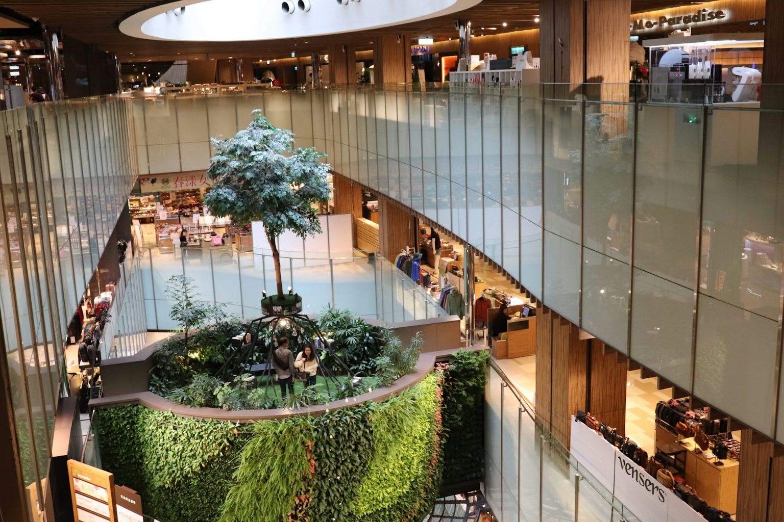 Intérieur d'un centre commercial moderne avec une végétation luxuriante et un arbre central