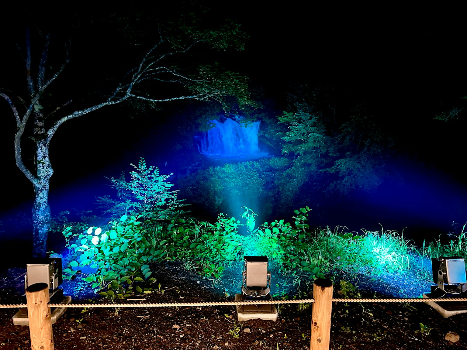 Escena nocturna con una cascada iluminada por luces azules