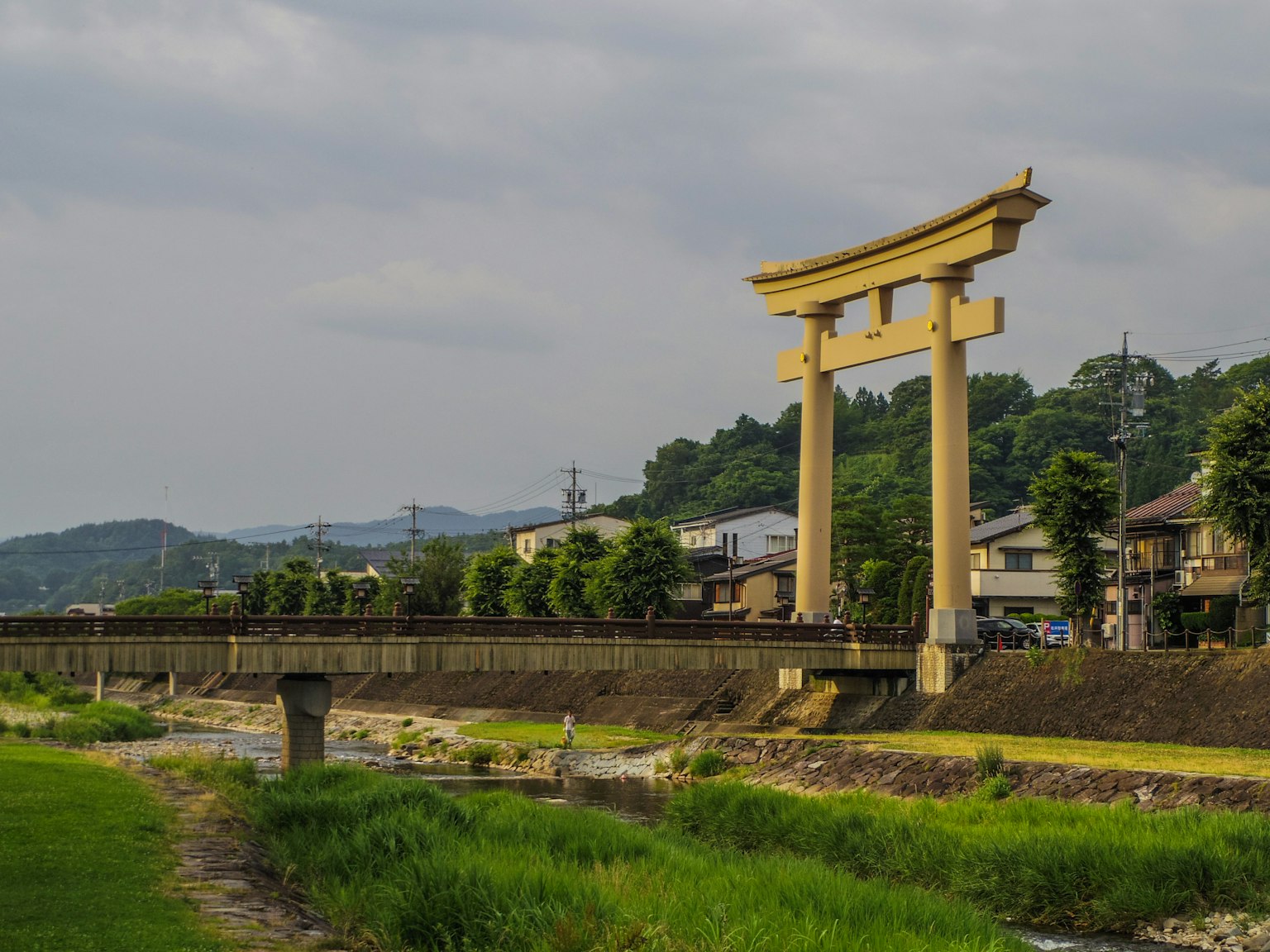 Grande porta torii vicino a un fiume circondata da vegetazione lussureggiante