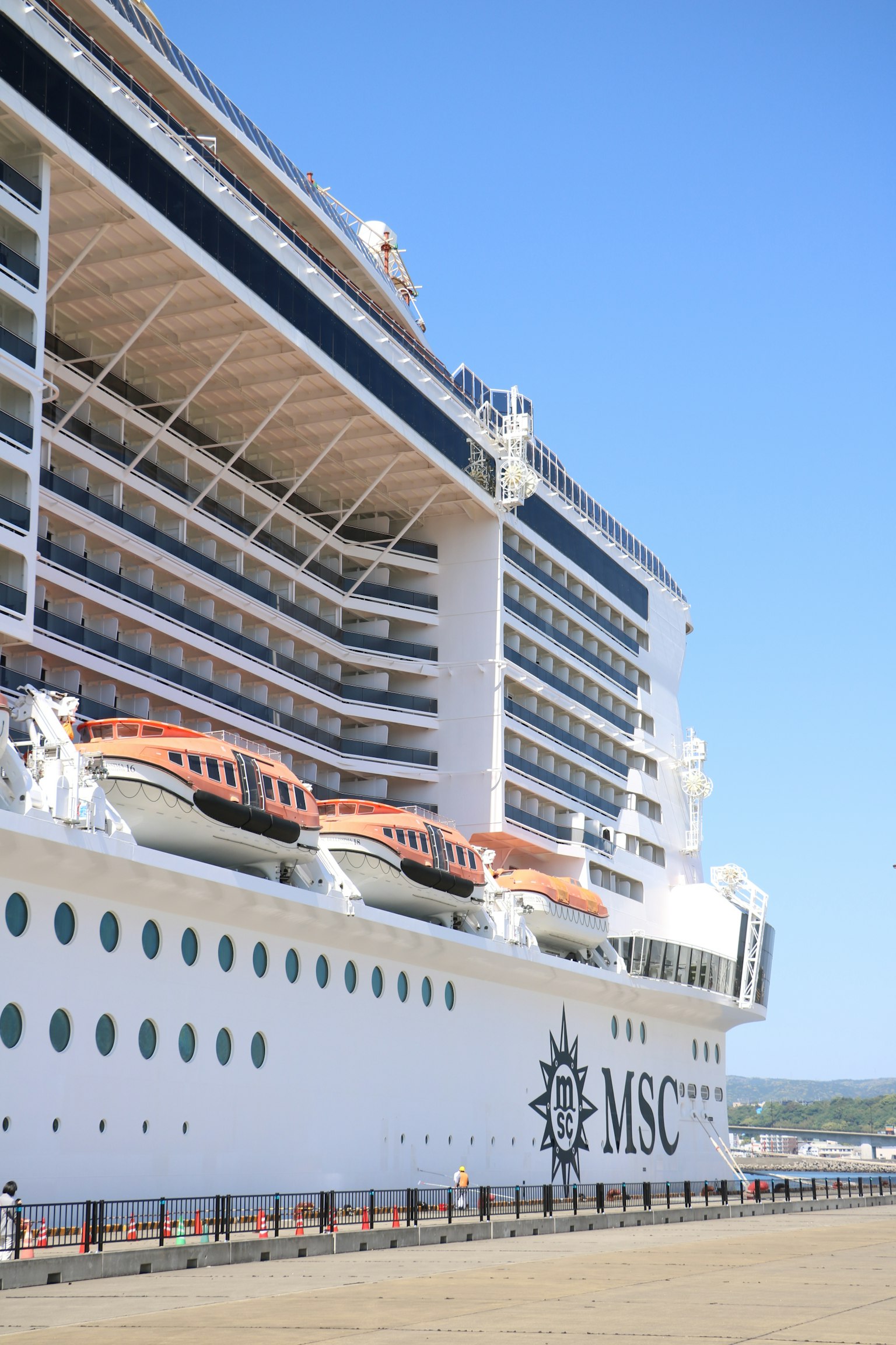 Seitenansicht eines MSC-Kreuzfahrtschiffes, das unter einem klaren blauen Himmel angedockt ist