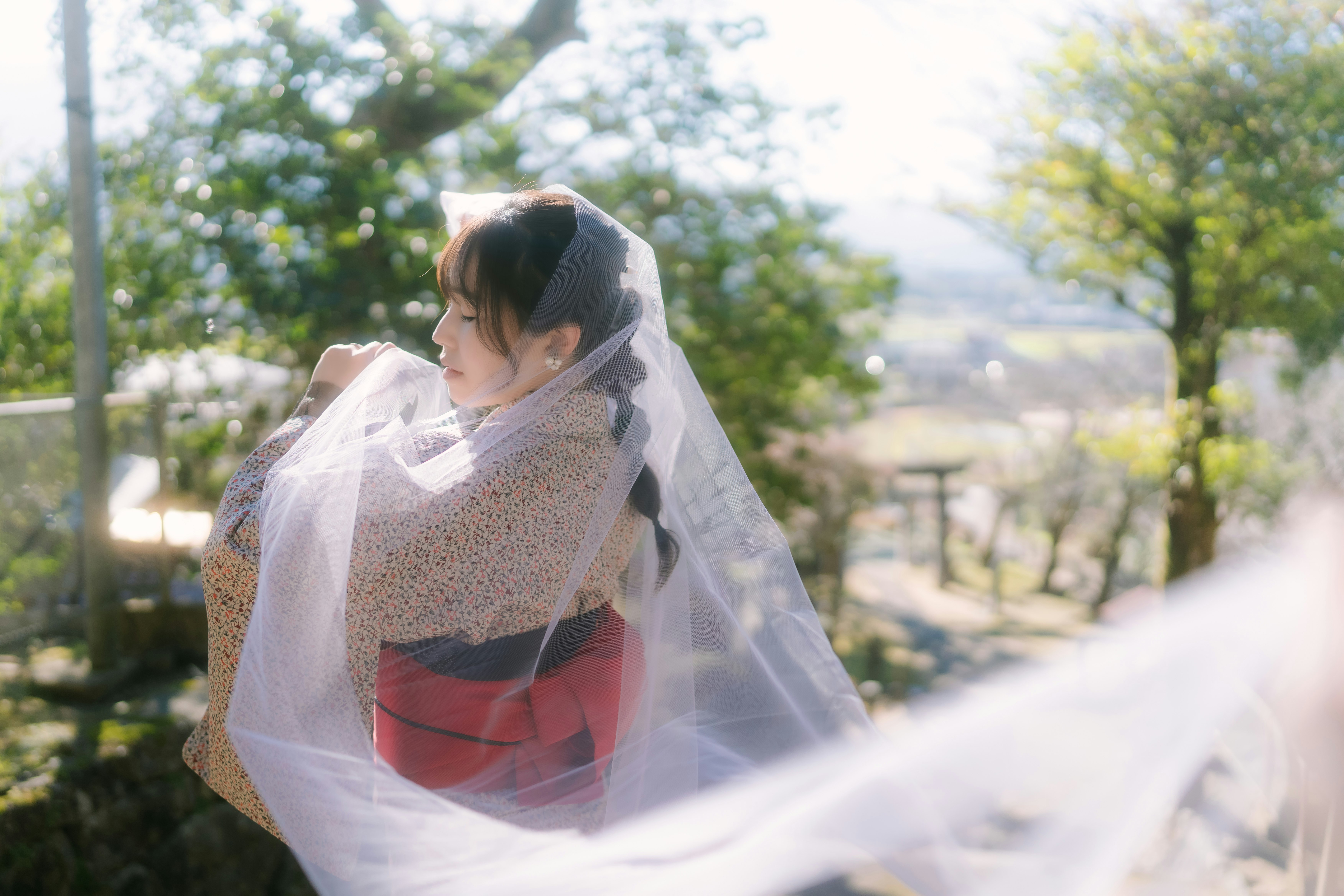 木々の中でベールをかぶる女性の後ろ姿