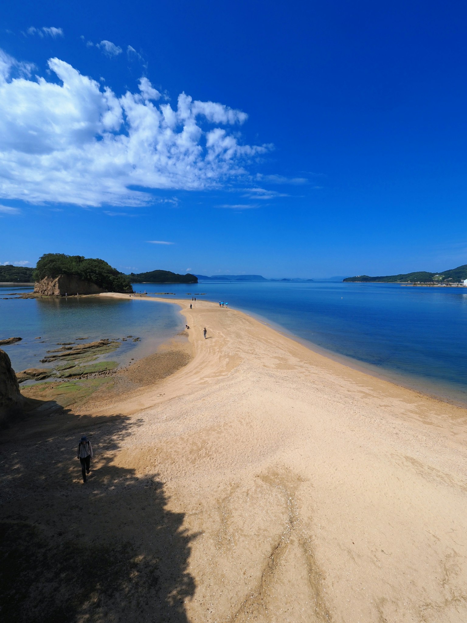 Pantai berpasir yang membentang ke perairan biru tenang di bawah langit cerah