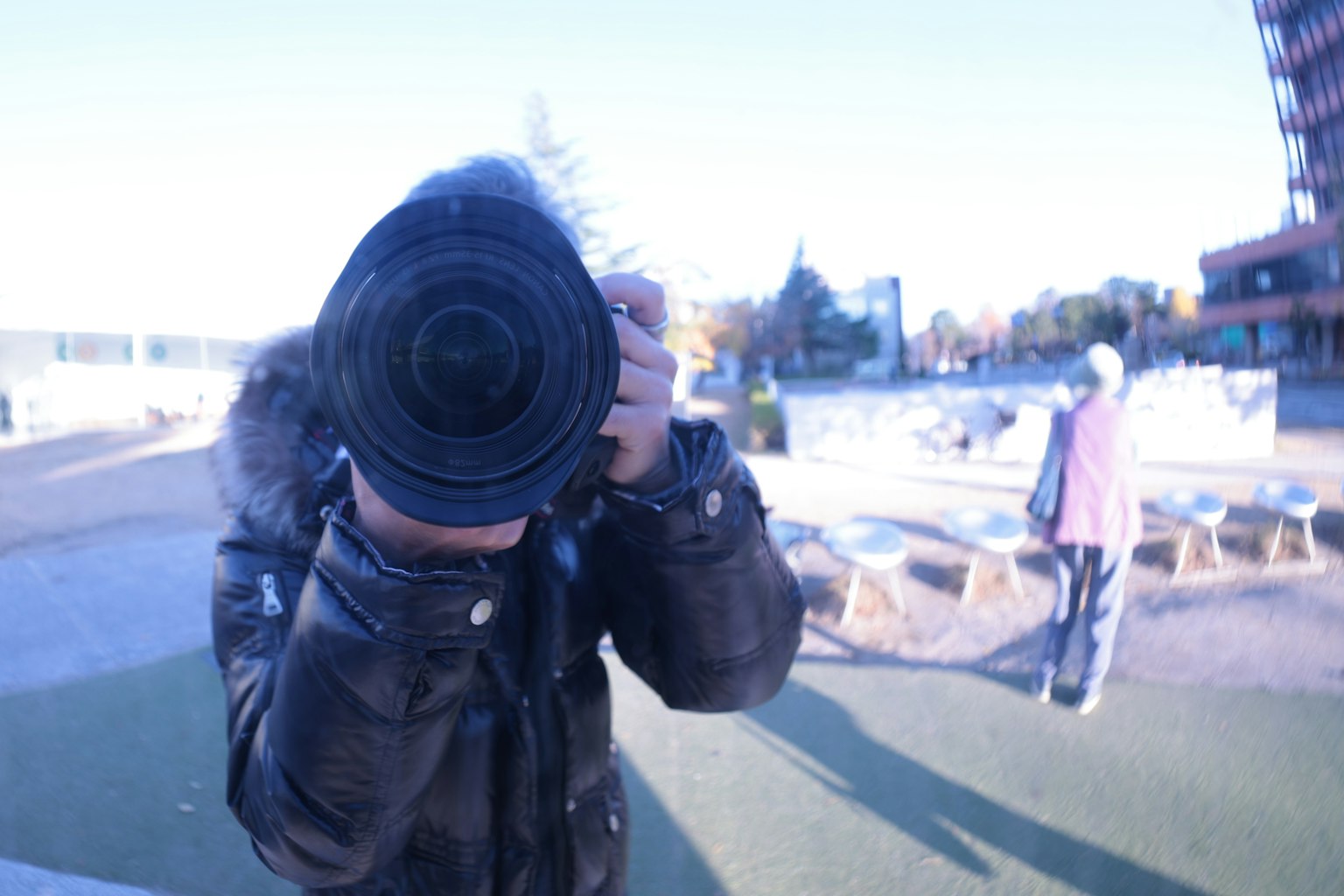 カメラを持つ人物がレンズを向けている写真 背景には他の人々が見える