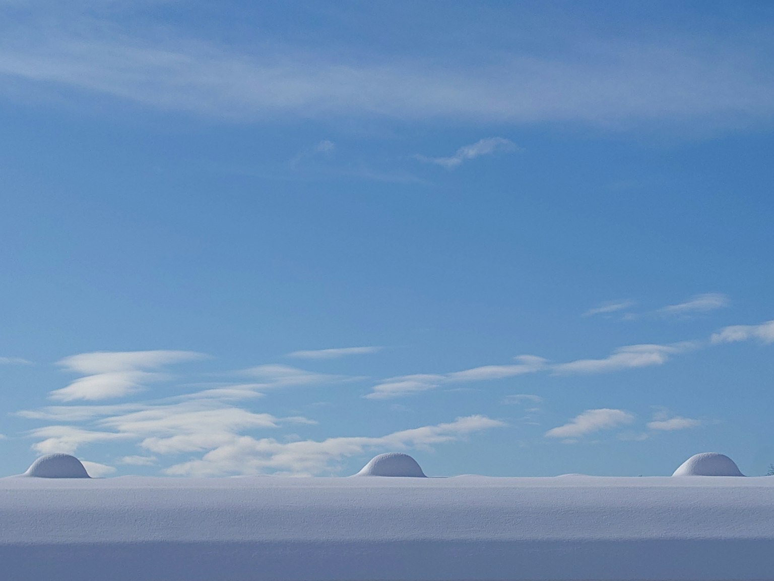 Colline couverte de neige sous un ciel bleu clair avec des nuages blancs
