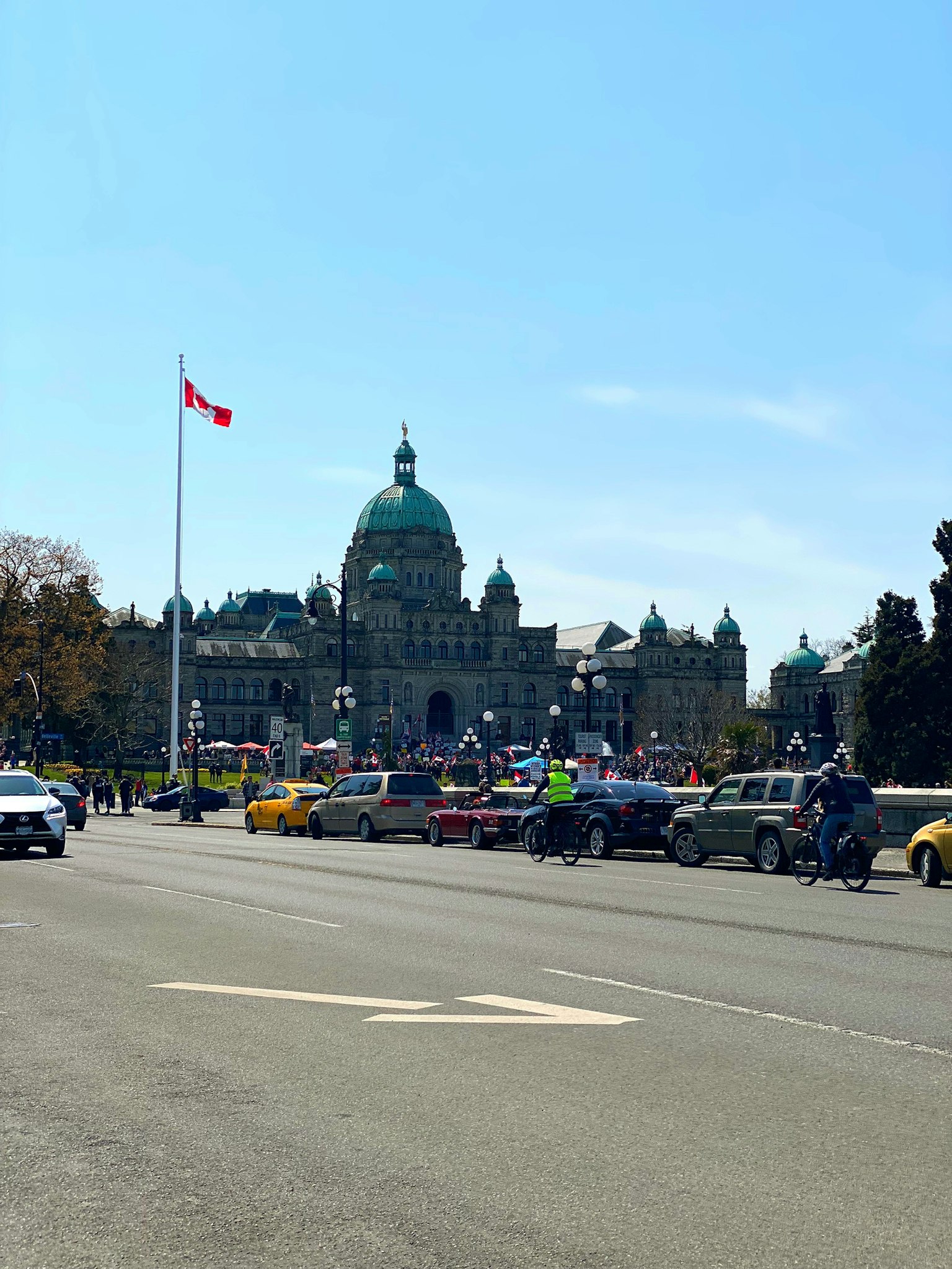 Pemandangan Gedung Parlemen British Columbia dengan bendera Kanada dan jalan yang sibuk