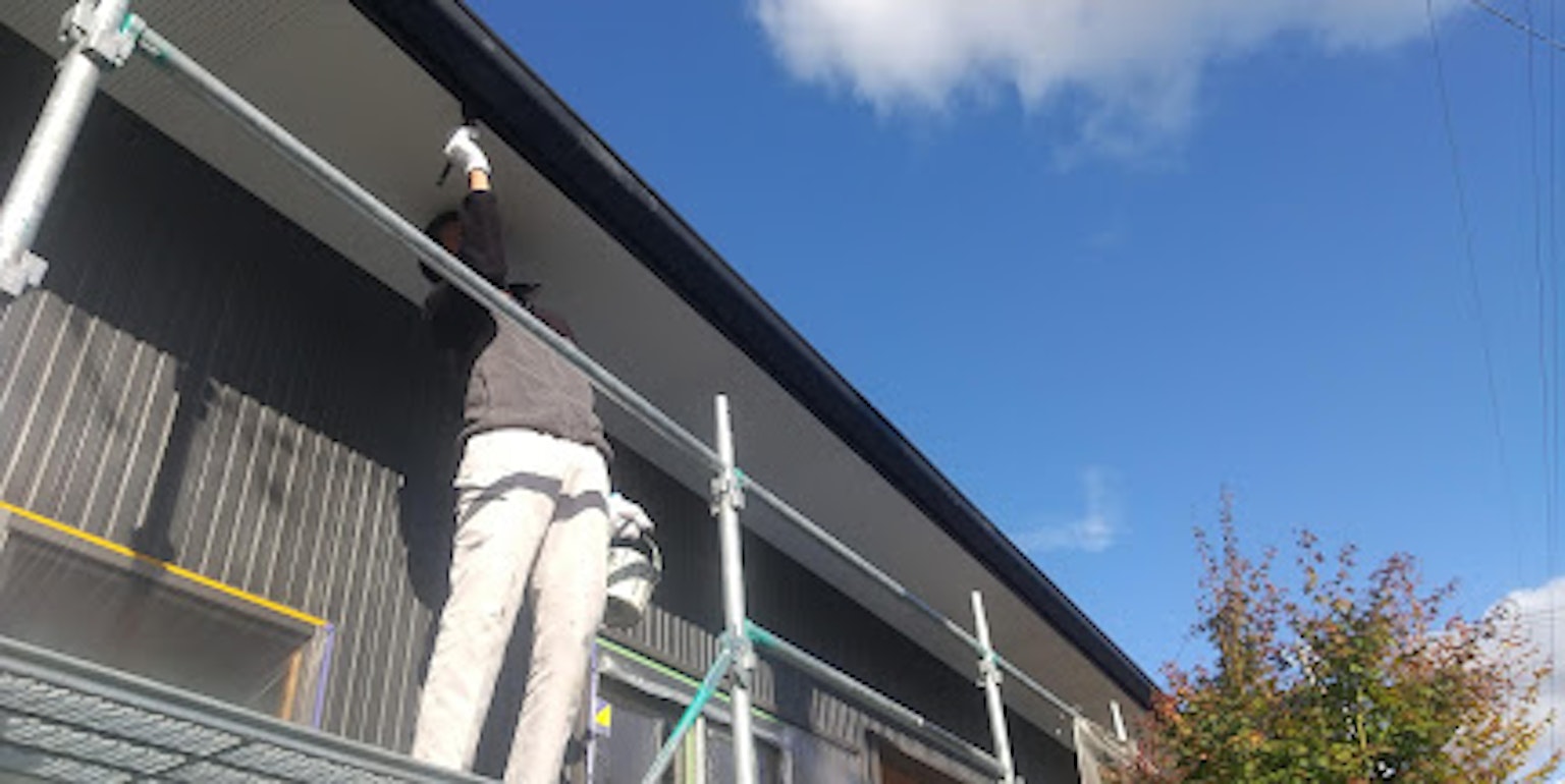 Une personne travaillant sur un échafaudage en train de peindre l'extérieur d'un bâtiment