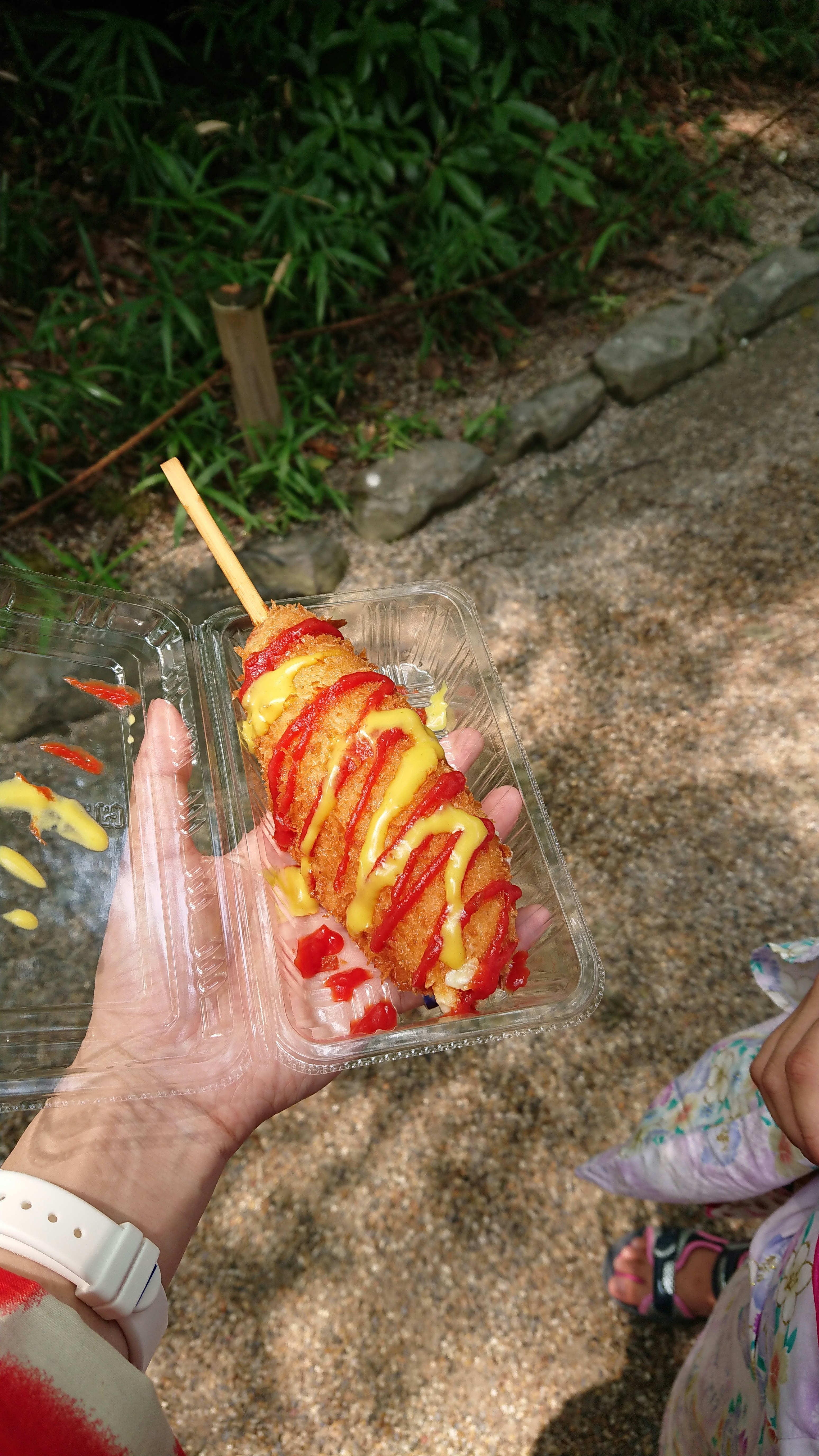 postre tipo brocheta en la mano sobre una calle empedrada