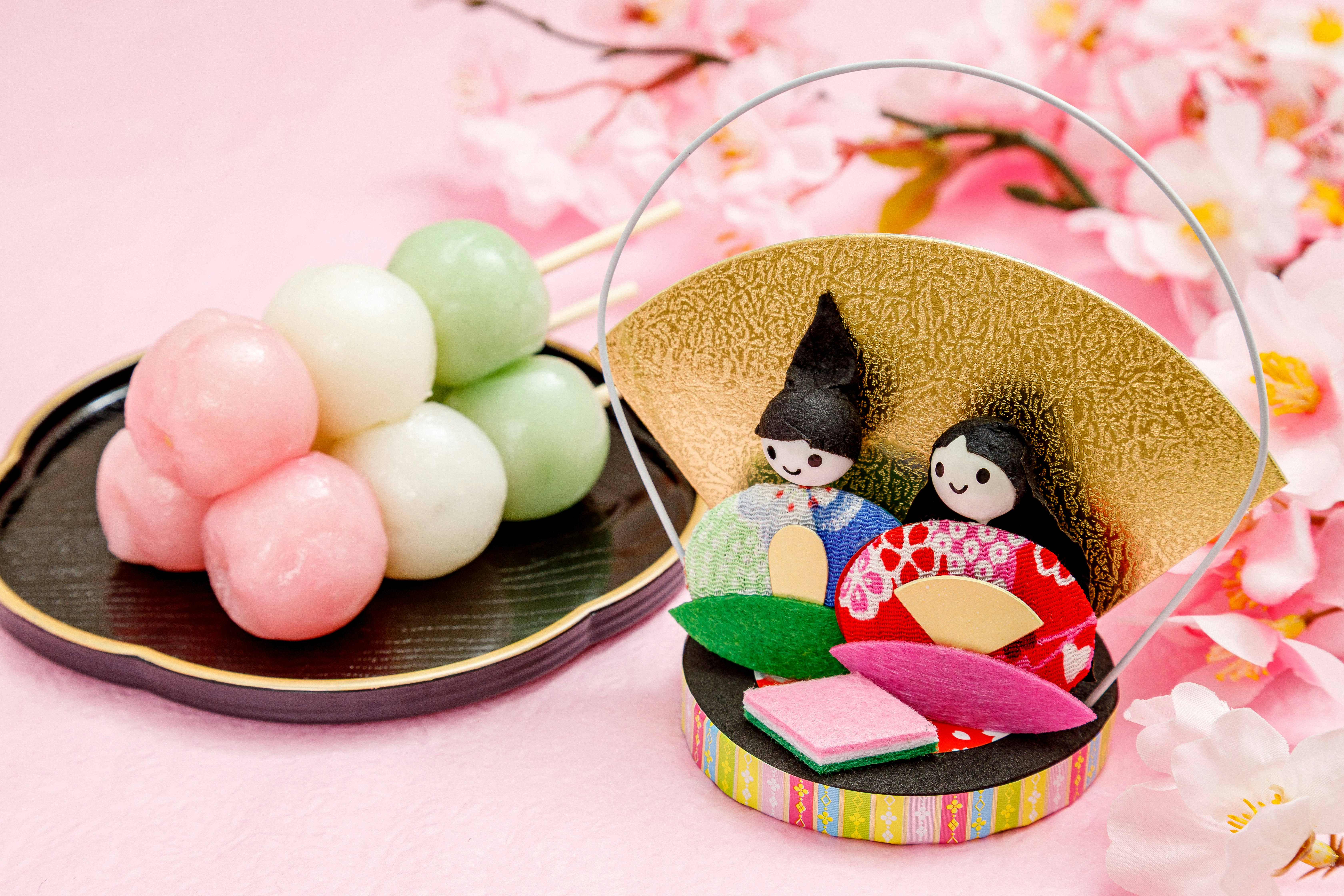 Ensemble de wagashi aux poupées hina sur fond de fleurs de pêcher