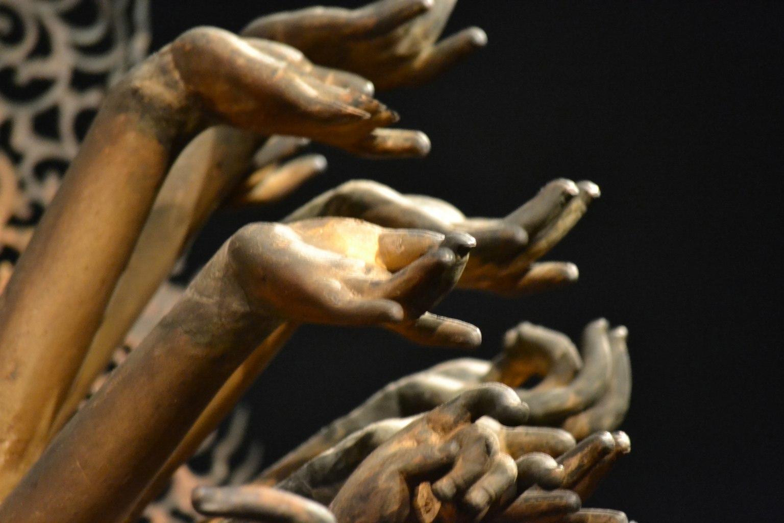 Sculpture artistique avec de nombreuses mains dorées tendues vers l'extérieur