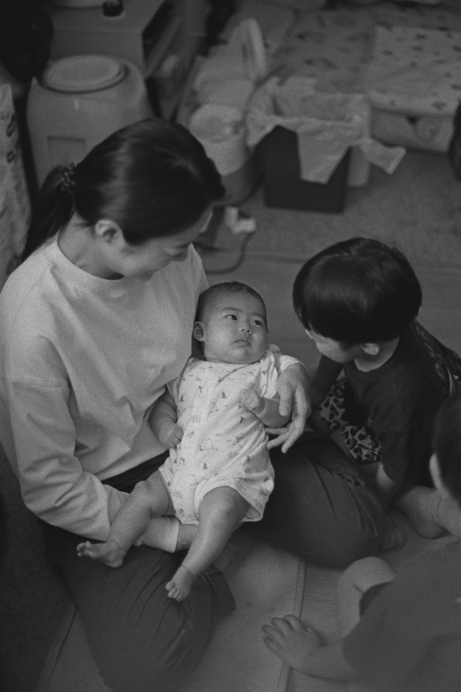 母親が赤ちゃんを抱きしめているシーン 兄弟がそばにいる 家の中の温かい雰囲気