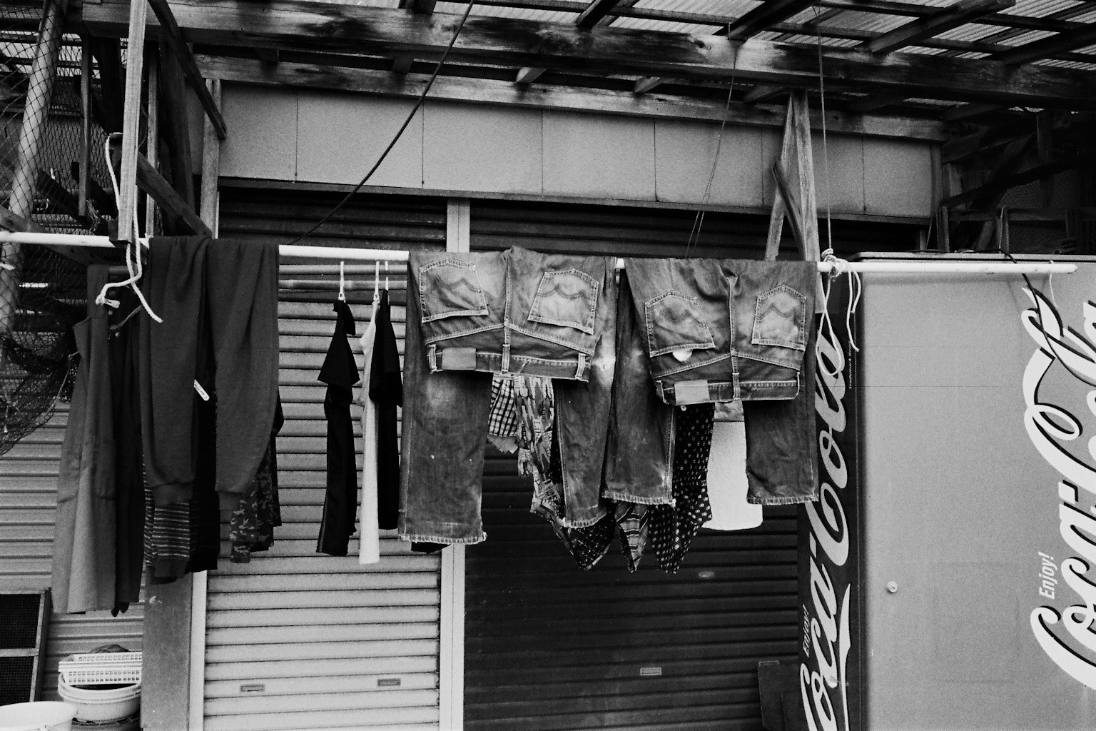 Außenszene mit hängenden Kleidern Jeans und Hemden ausgestellt Coca-Cola-Schild sichtbar