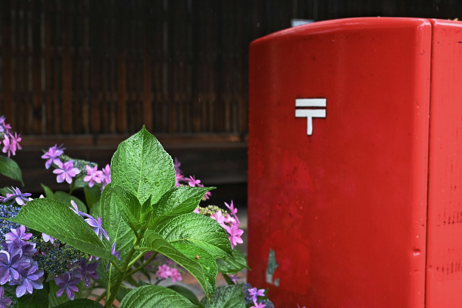 赤い郵便ポストと色とりどりの花がある風景