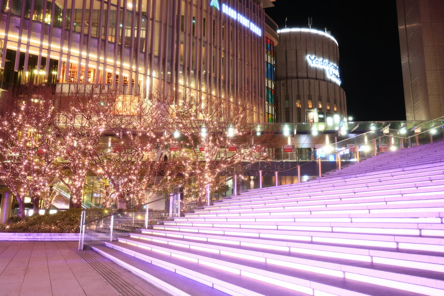Escalera iluminada con luces rosas en una ciudad nocturna